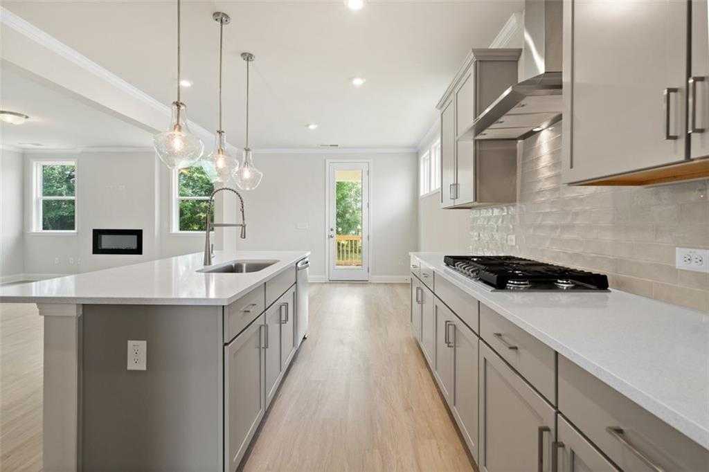 Modern kitchen with white shaker cabinets, quartz island, stainless appliances, subway tile backsplash in Davidson Homes The Willow D at Wehunt Meadows, Hoschton, GA