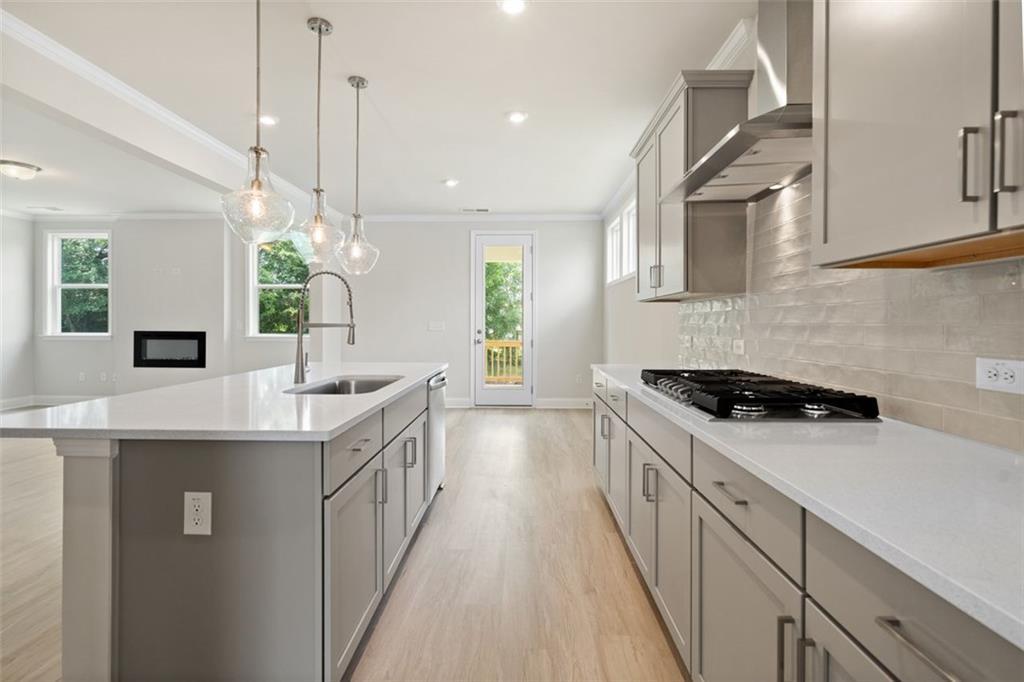Modern kitchen with white shaker cabinets, quartz island, stainless appliances, subway tile backsplash in Davidson Homes The Willow D at Wehunt Meadows, Hoschton, GA
