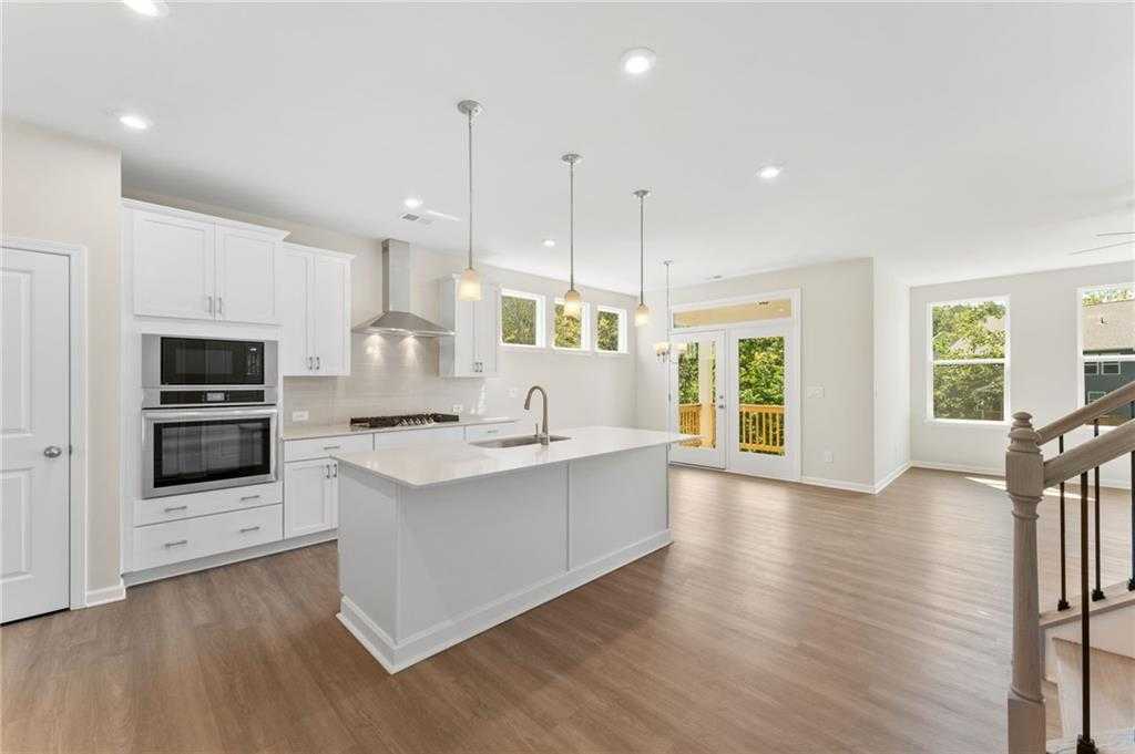Modern open-concept kitchen featuring white island, stainless double oven, and French doors in Davidson Homes The Ash B, Dallas, GA