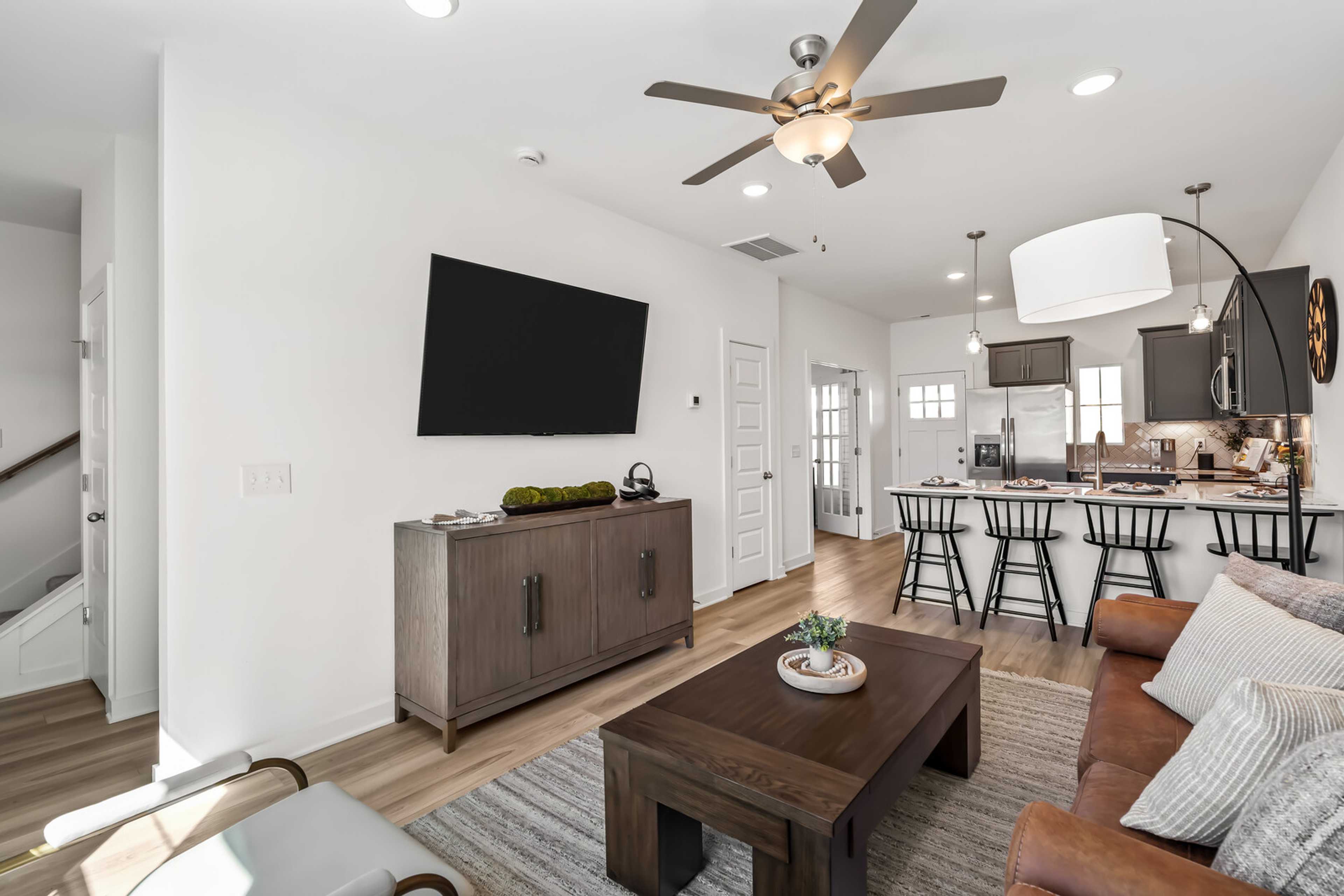 Open-concept living room and kitchen at The Towns at Red River in Gallatin TN with hardwood floors, modern island, and ceiling fan
