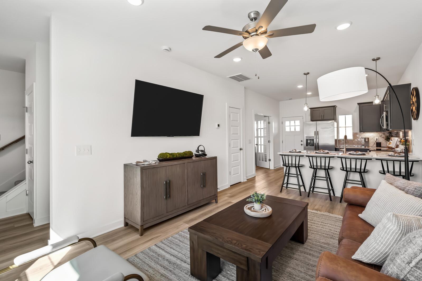 Open-concept living room and kitchen at The Towns at Red River in Gallatin TN with hardwood floors, modern island, and ceiling fan