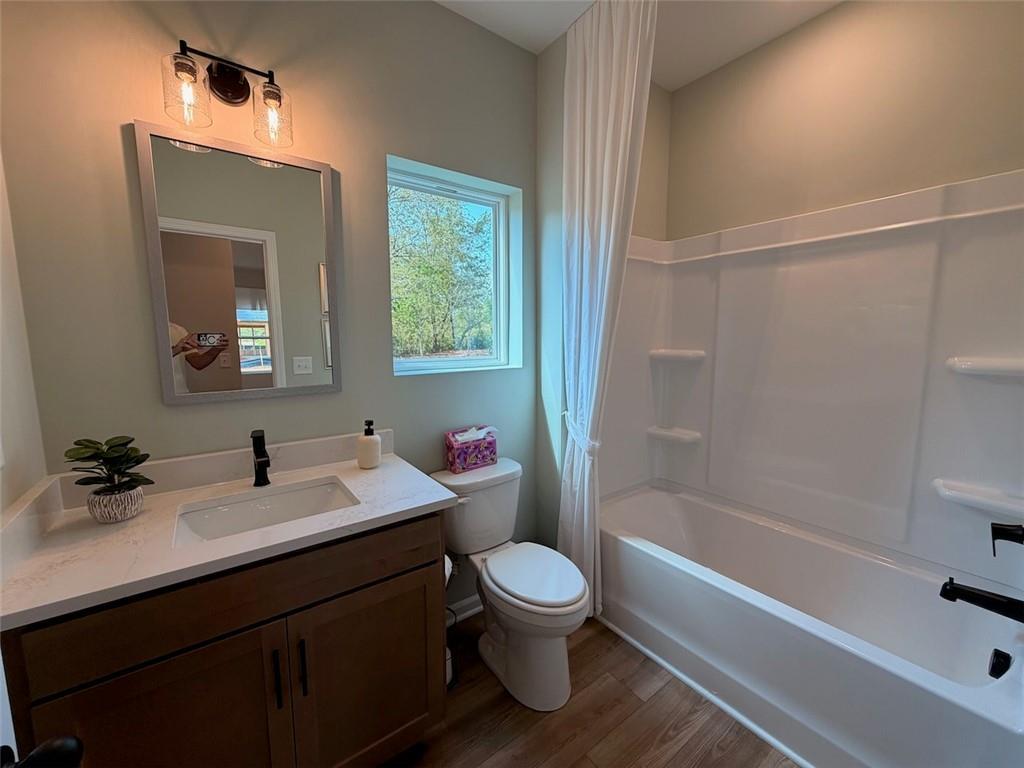 Modern bathroom with wood vanity, white quartz countertop, and tub shower combo in Davidson Homes Pinecrest J, Cartersville GA