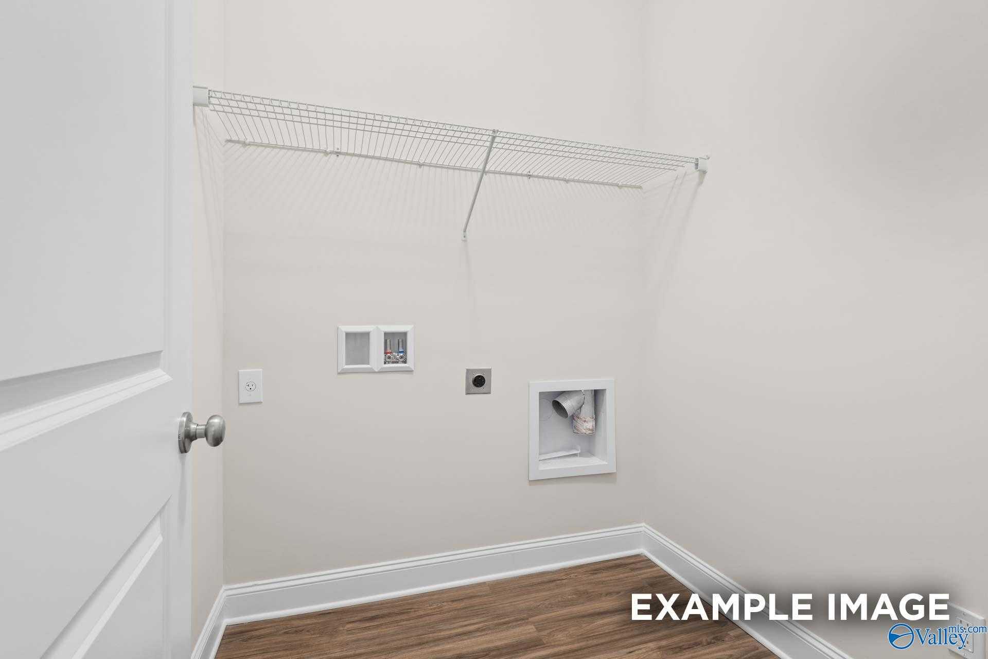 Spacious laundry room featuring wire shelving, utility sink, vents, and hardwood floors in Davidson Homes The Franklin, Meridianville, Alabama