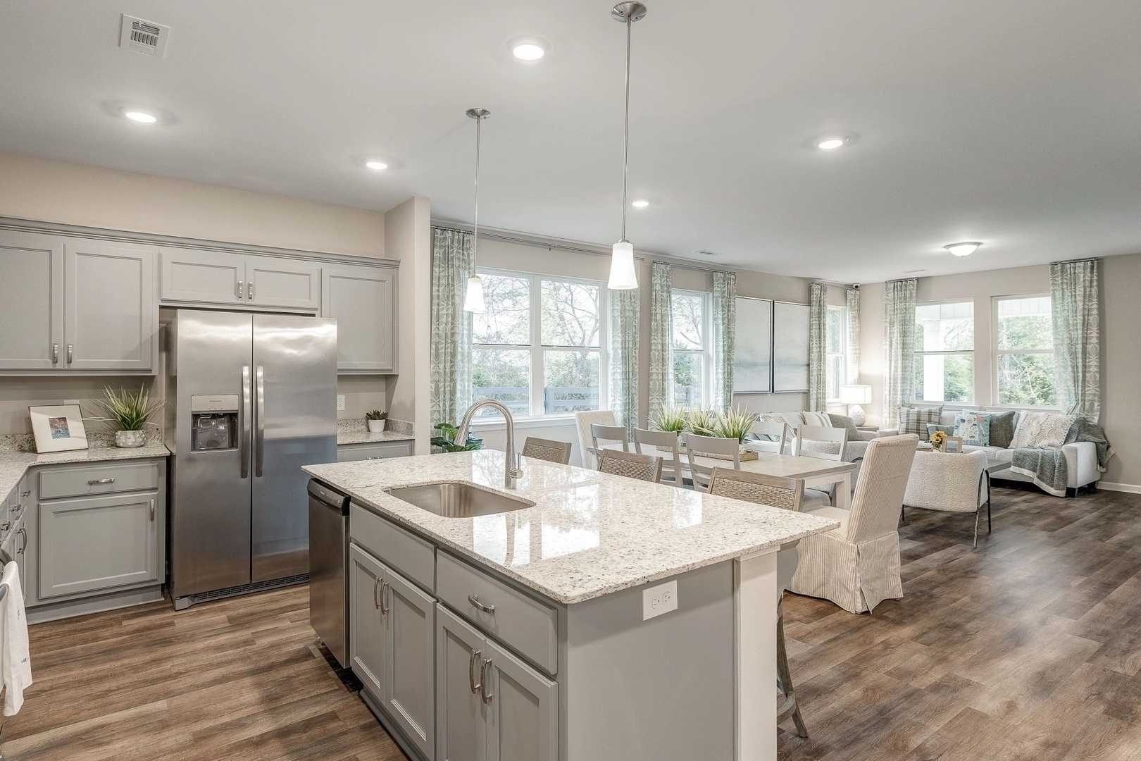 Open-concept kitchen and dining in Carroll Green, Harvest AL with gray cabinets, quartz island, stainless appliances, hardwood floors