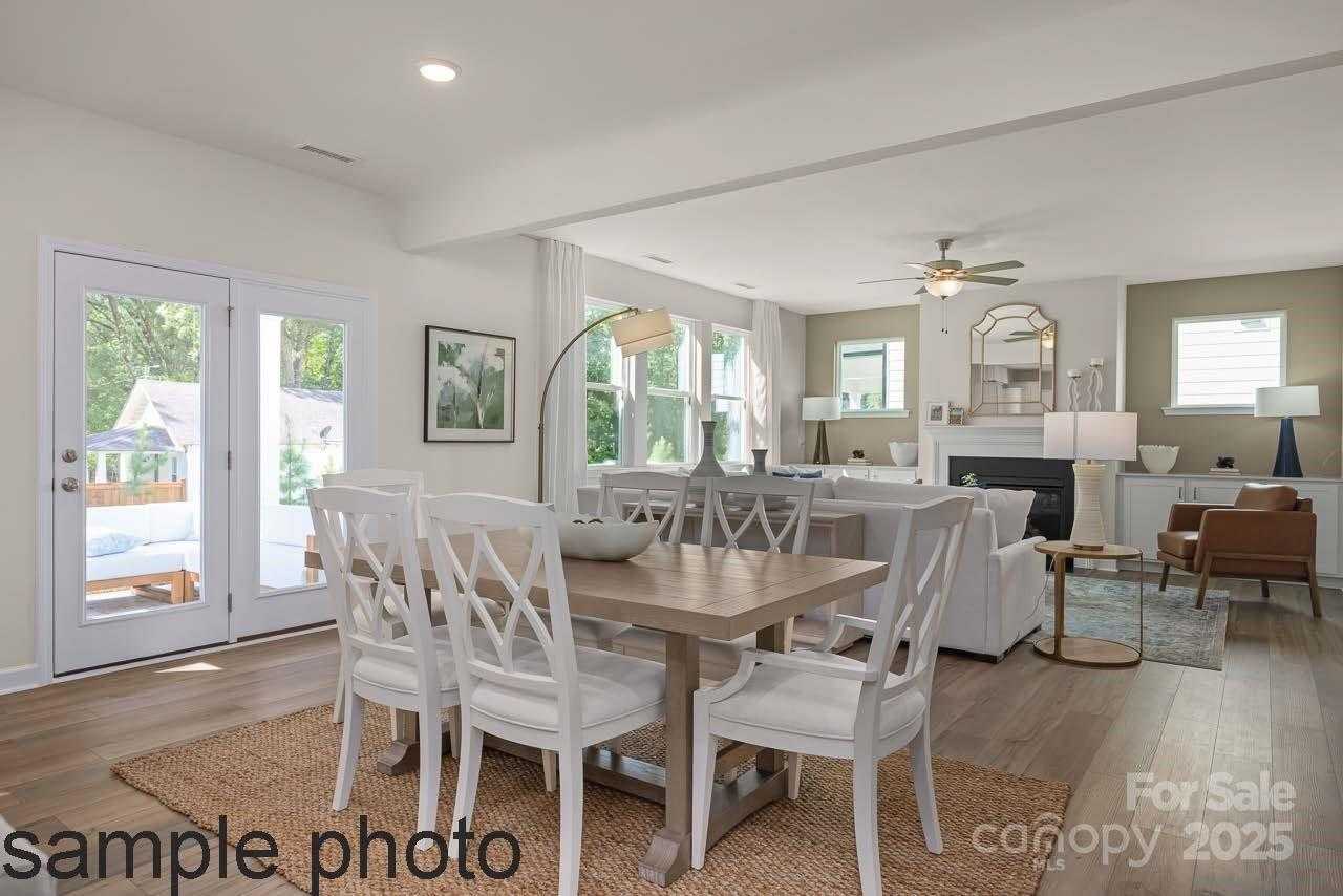 Open-concept dining-living area with farmhouse table, white chairs, fireplace, and French doors to patio in Davidson Homes Hickory E II, Belmont NC