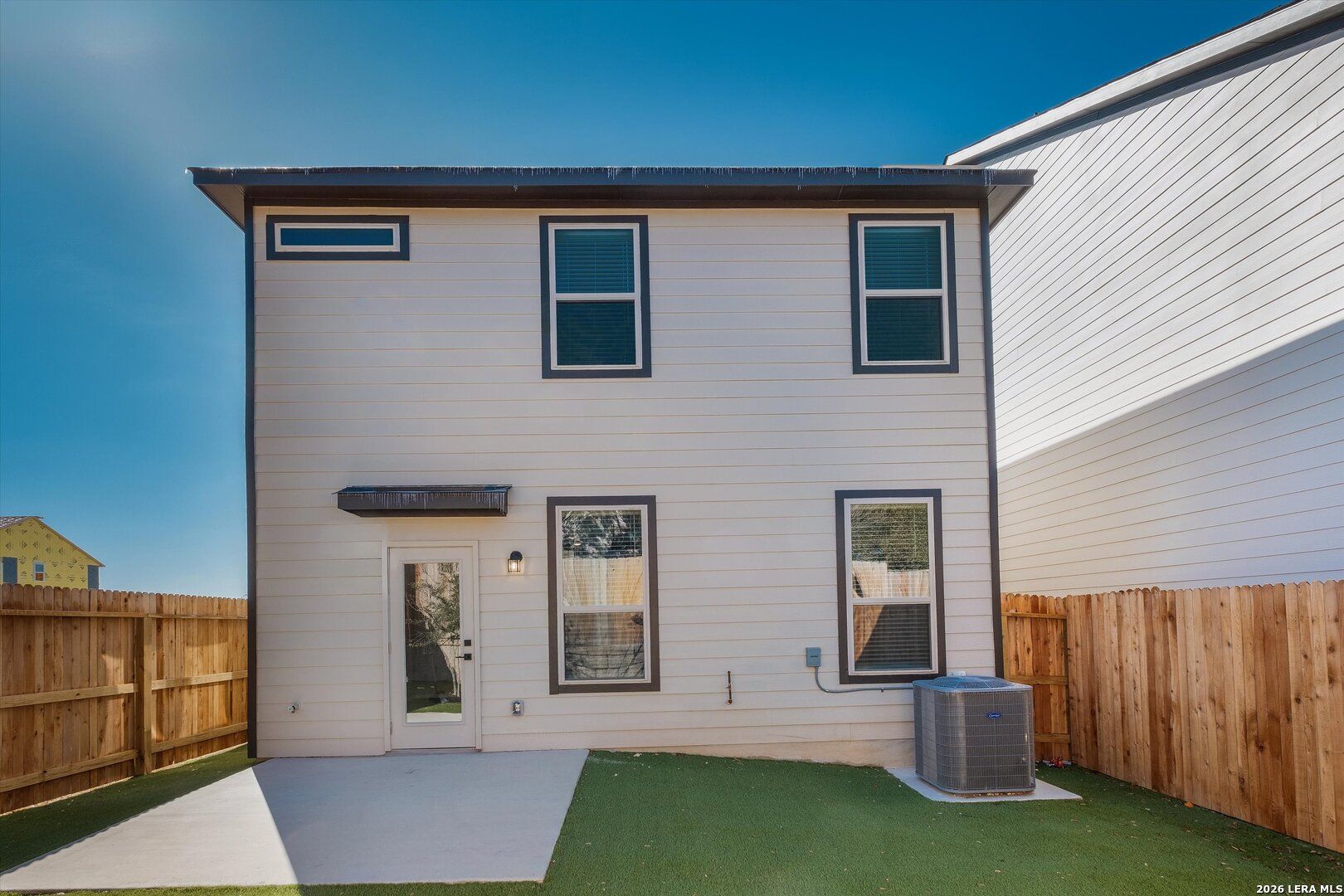 Covered back patio and fenced backyard with green turf in Davidson Homes The Charlotte A 2-story home, San Antonio, Texas