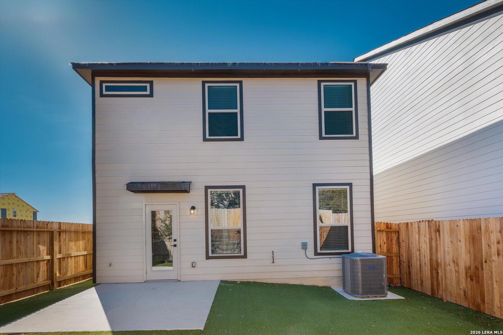 Covered back patio and fenced backyard with green turf in Davidson Homes The Charlotte A 2-story home, San Antonio, Texas
