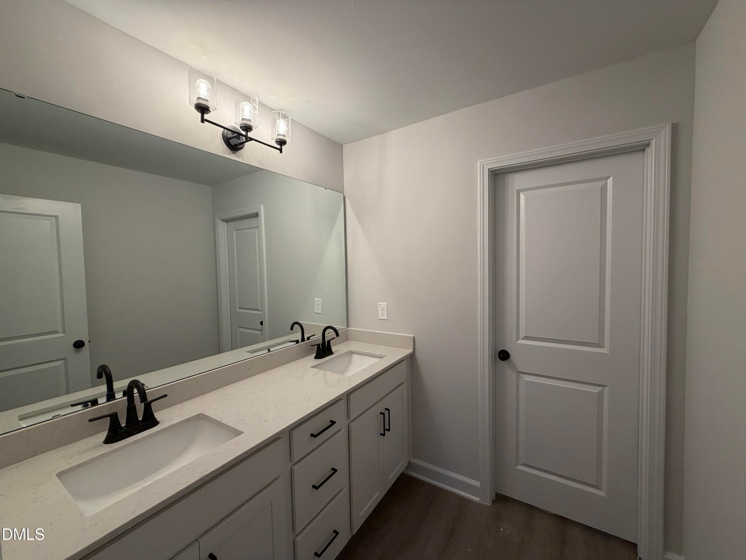 Double vanity bathroom with quartz countertops, matte black fixtures, and large mirror in Davidson Homes The Preston C, Wendell Ridge, NC