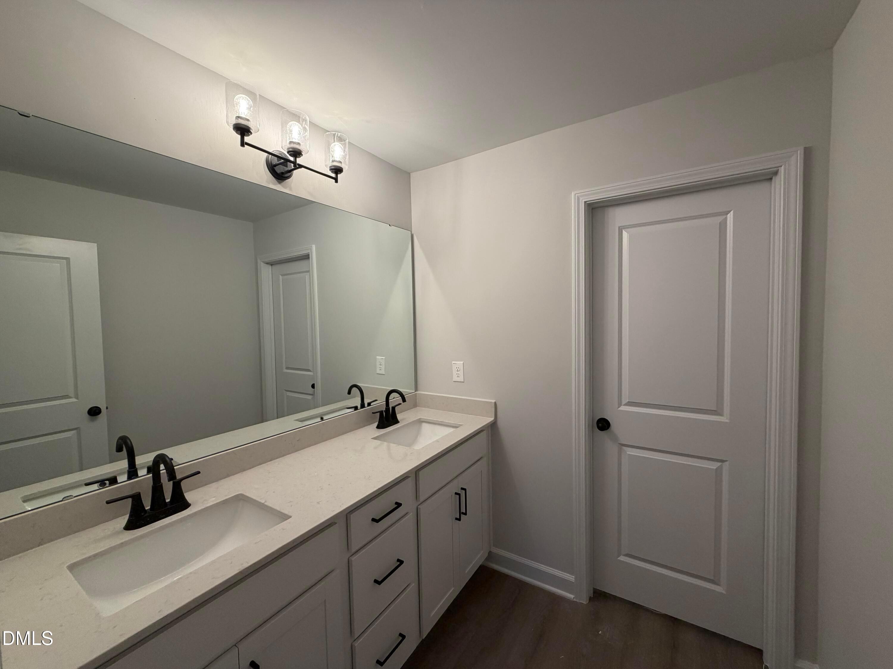 Double vanity bathroom with quartz countertops, matte black fixtures, and large mirror in Davidson Homes The Preston C, Wendell Ridge, NC
