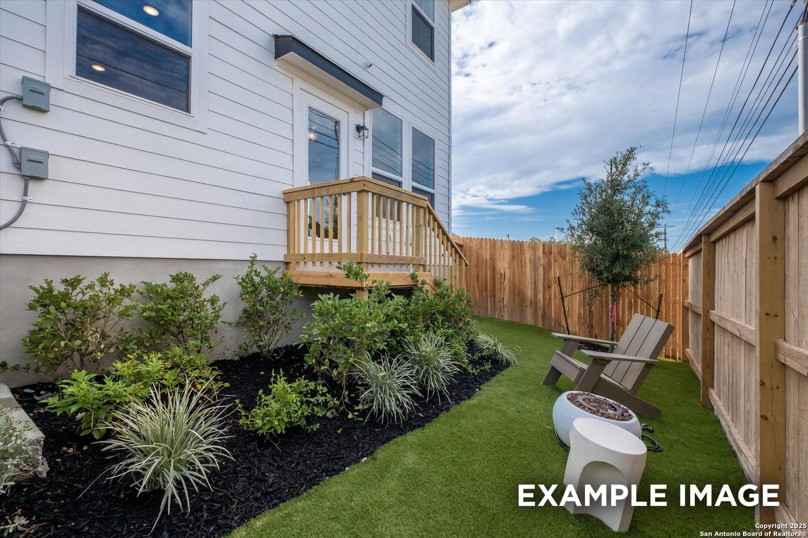Private backyard deck with Adirondack chair, fire pit, artificial turf, shrubs and fence in The Florence C 3-bedroom home, Meadows at Oak Creek, San Antonio