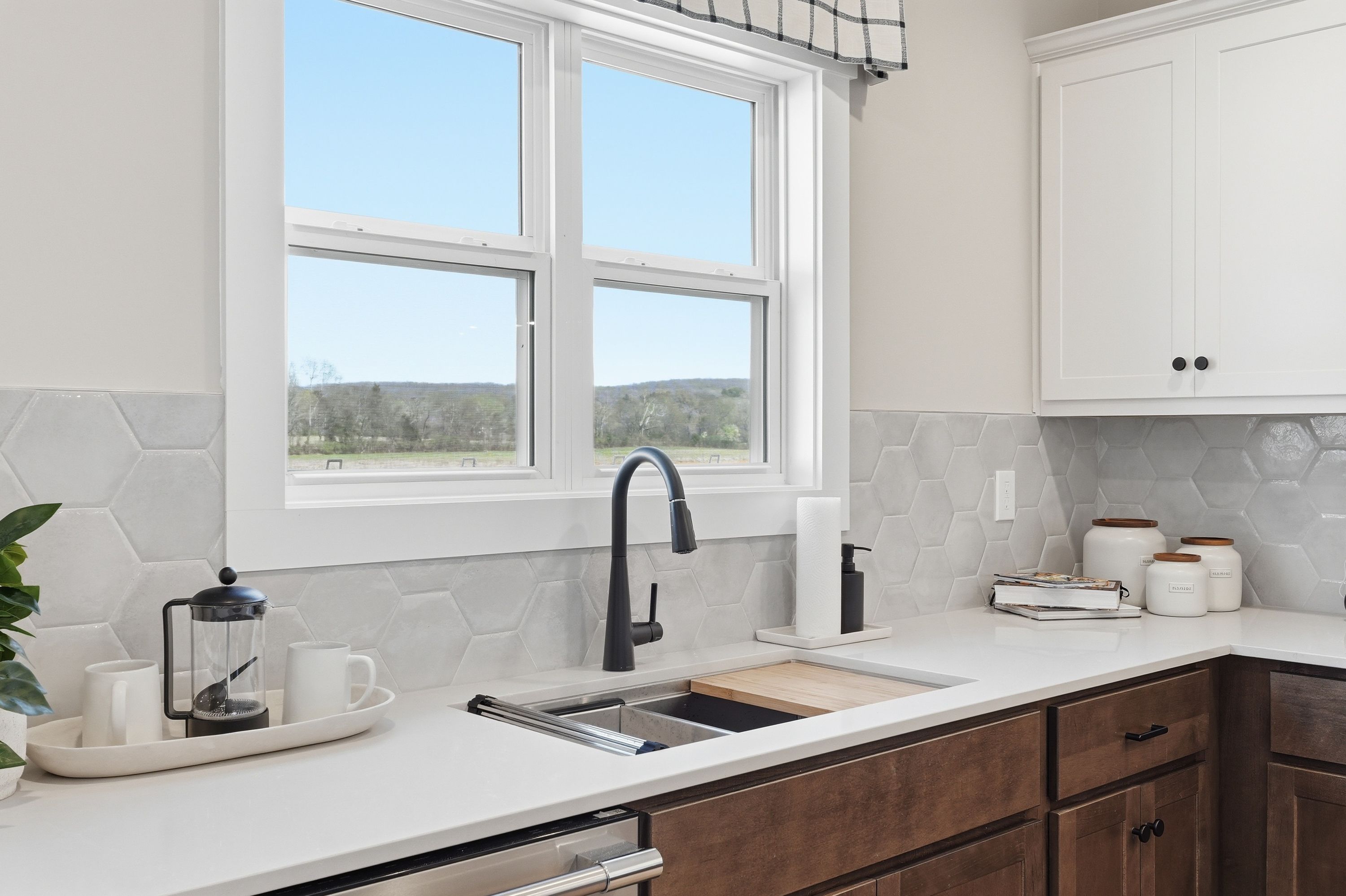 Modern Berry Cove kitchen in New Market AL featuring white shaker cabinets, gray hexagonal tile backsplash, farmhouse sink and rural window view