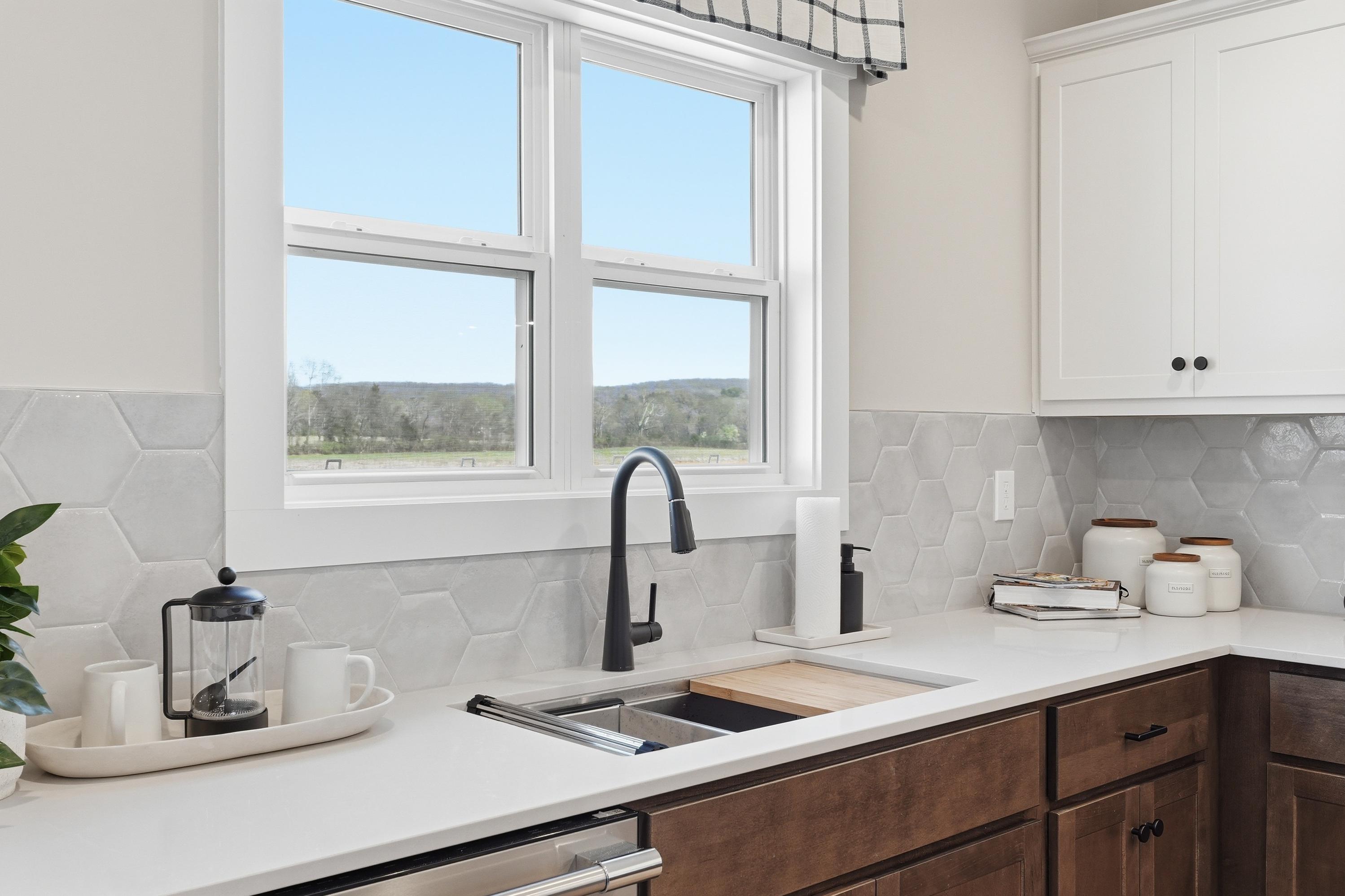 Modern Berry Cove kitchen in New Market AL featuring white shaker cabinets, gray hexagonal tile backsplash, farmhouse sink and rural window view