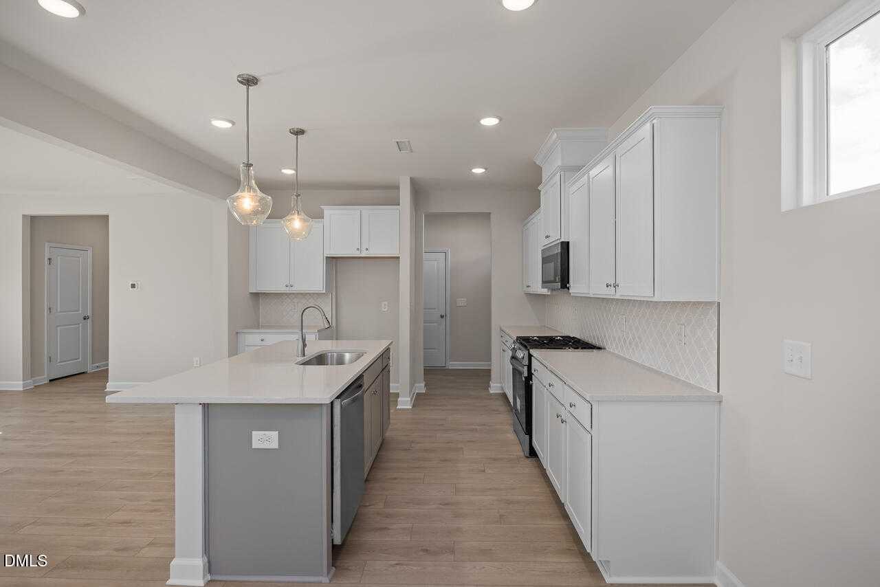 Modern kitchen featuring white shaker cabinets, quartz island, stainless appliances in The Gavin C floor plan, Lillington, NC