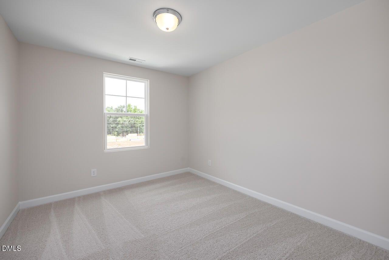 Bright, carpeted secondary bedroom in The Graham Interior floor plan at Springvale, Fuquay-Varina, North Carolina.