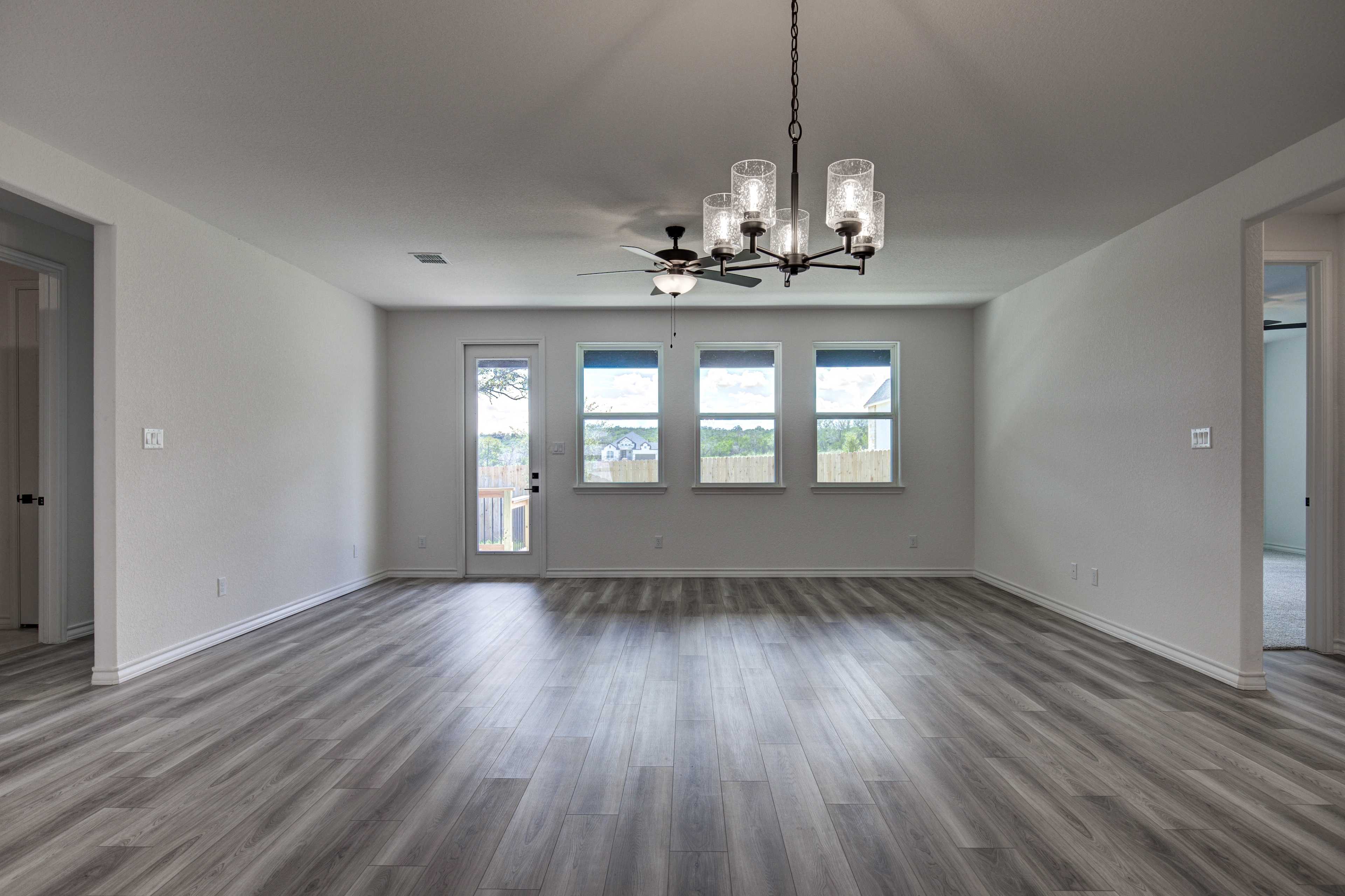 Spacious open-concept living room in The Lanier with luxury vinyl plank floors, large windows, chandelier, and ceiling fan