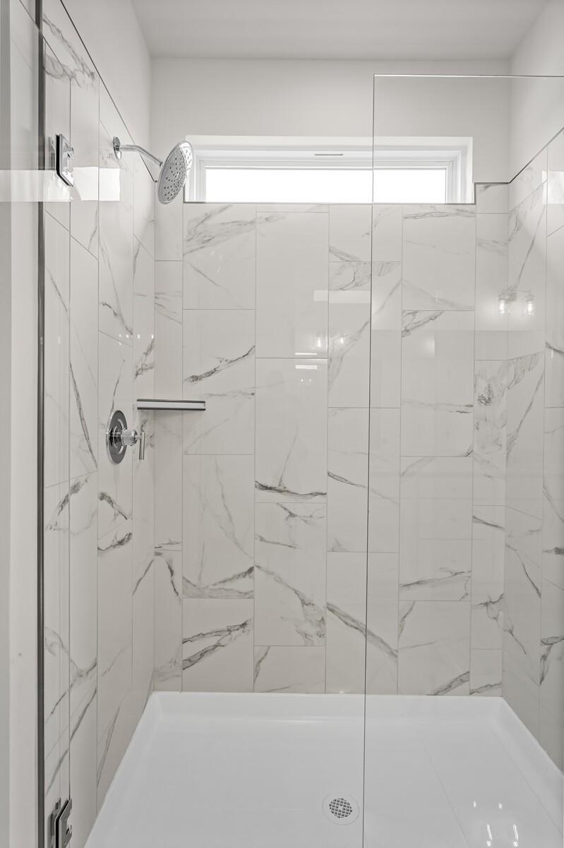 Walk-in shower with white marble tile and glass door in a Davidson Homes Ridgeport D floor plan in Mt. Juliet, Tennessee.