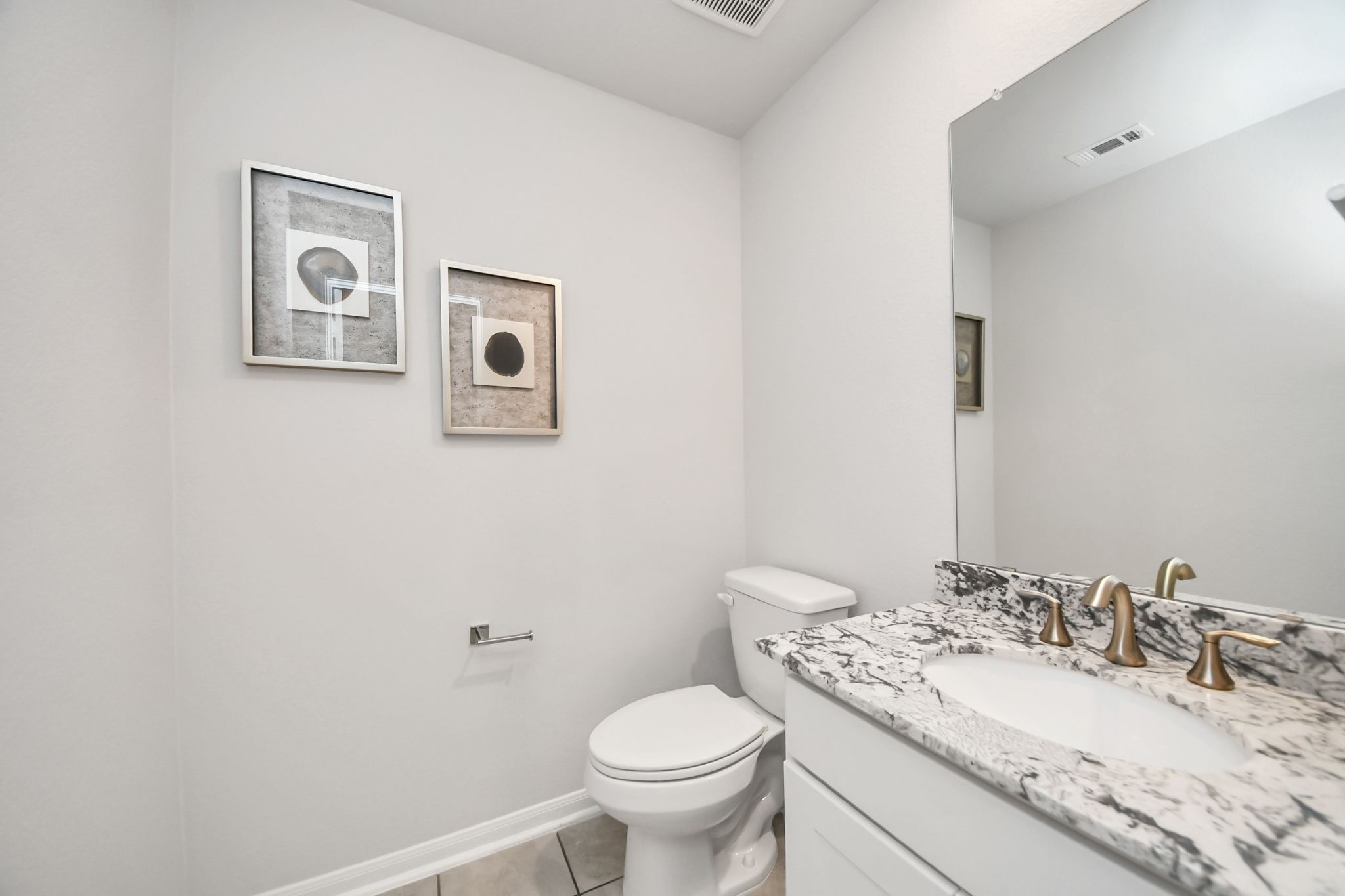 Modern powder room at Sunterra in Katy, TX by Davidson Homes featuring granite countertops and gold faucet fixtures.