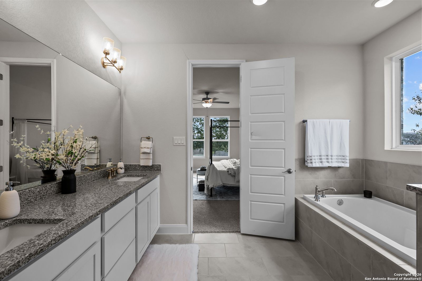 Elegant master bathroom with double granite vanity, freestanding tub, open to bedroom in Davidson Homes The Lanier H, Ladera, San Antonio