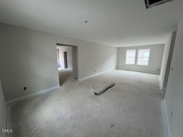 Spacious unfinished living room with beige walls, open archways, double windows, and rolled carpet in 4-bedroom Davidson Homes Preston A, Lillington, NC