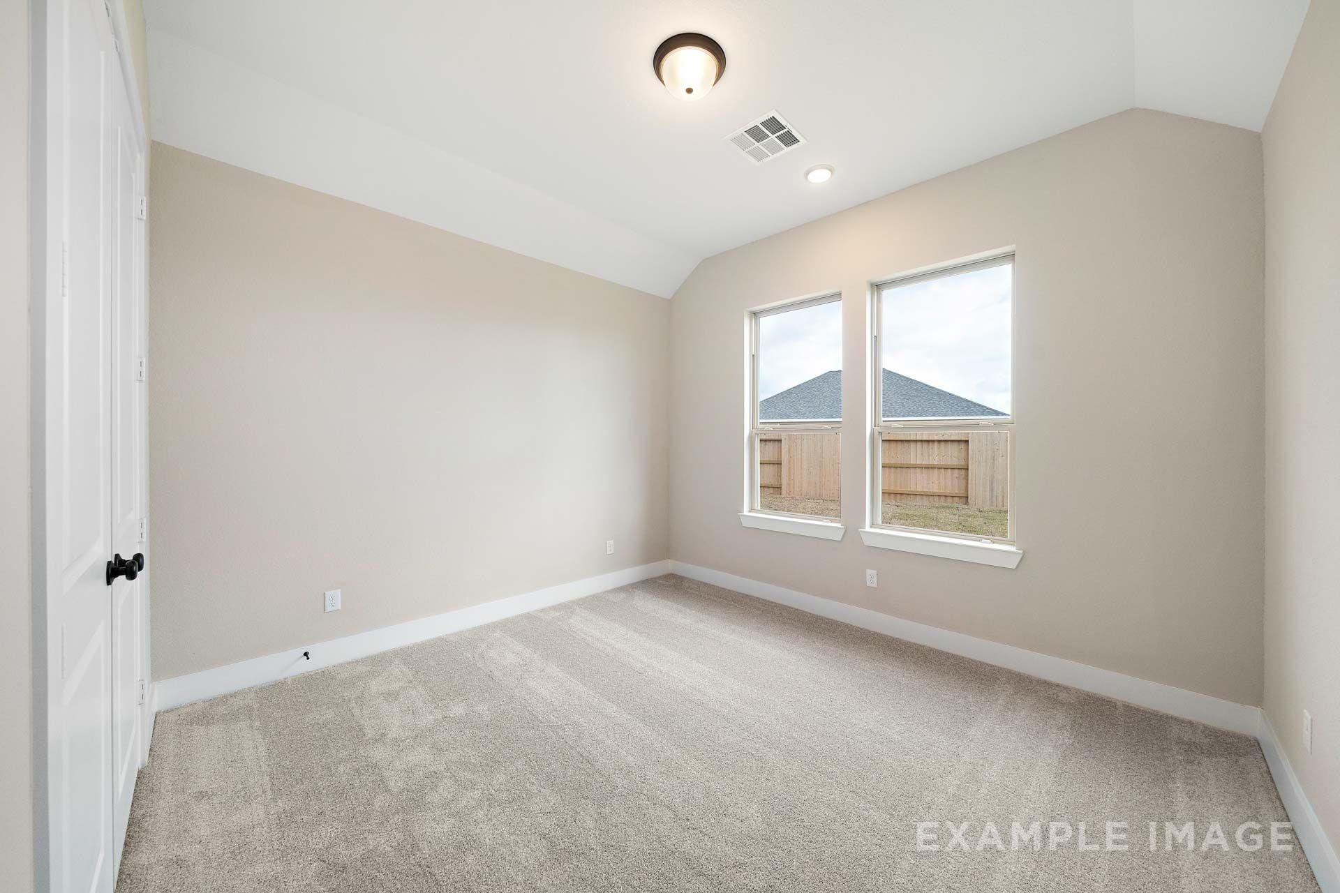 Spacious carpeted bedroom with dual windows in The Elizabeth, a Davidson Homes single-family design in Texas City, TX