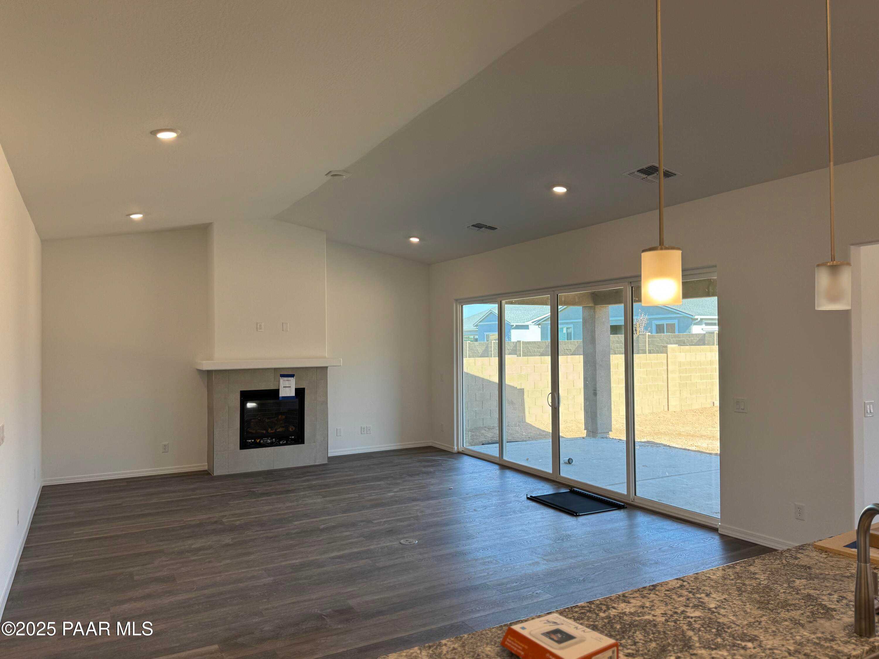 Open living room featuring modern white fireplace, sliding doors to covered patio, and hardwood floors in Davidson Homes Sunrise II A, Prescott AZ