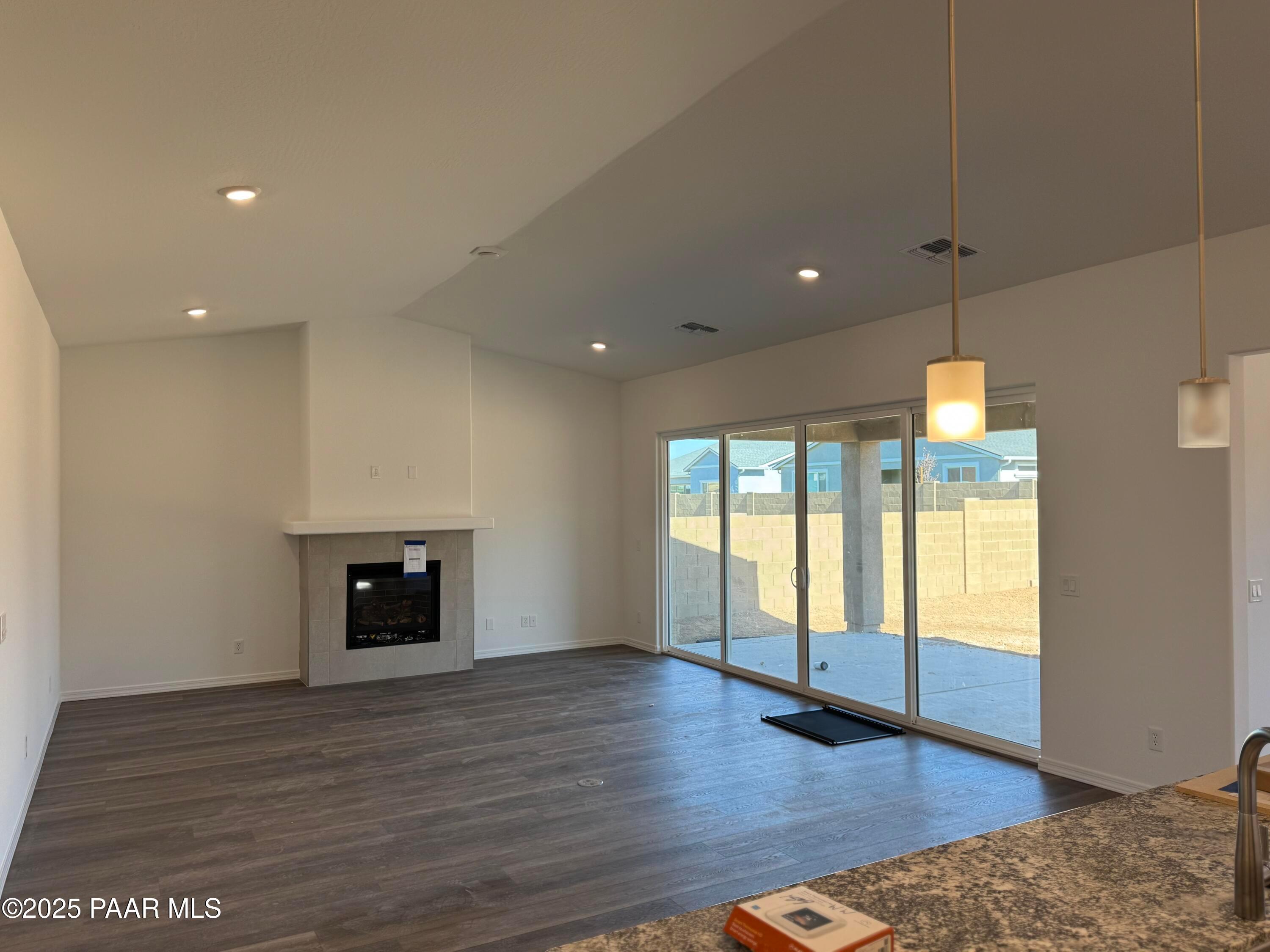 Open living room featuring modern white fireplace, sliding doors to covered patio, and hardwood floors in Davidson Homes Sunrise II A, Prescott AZ