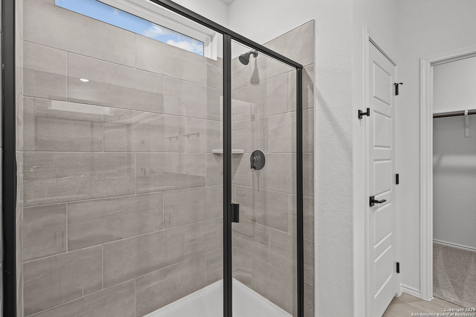 Modern frameless glass shower with gray subway tiles and rainfall head in master bath of Davidson Homes The Daphne J, Converse, Texas