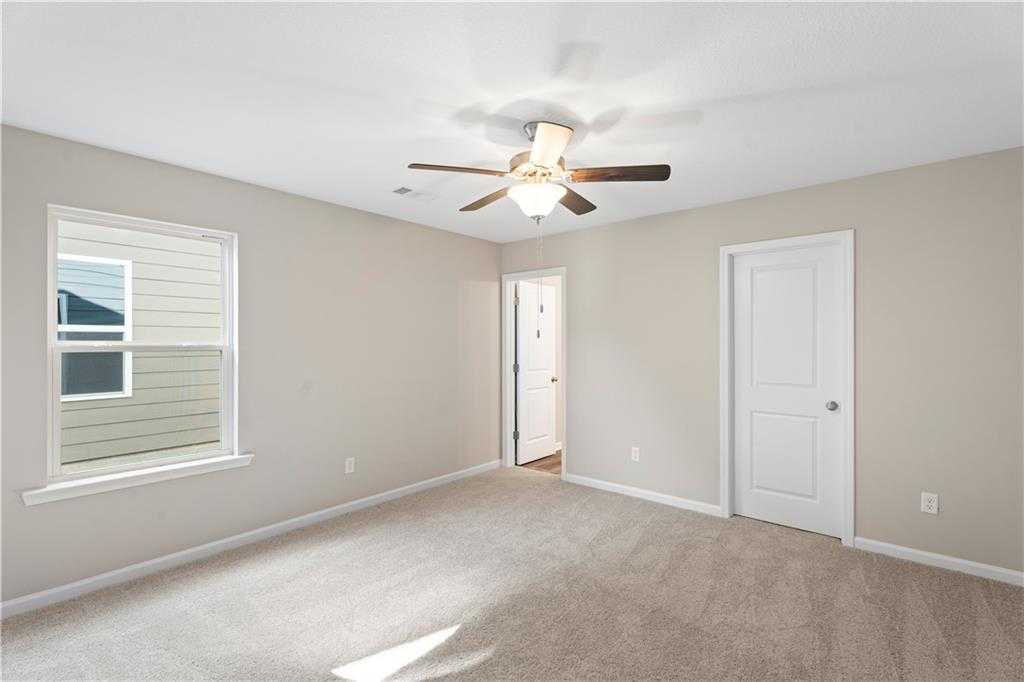 Bright secondary bedroom featuring ceiling fan, large window, beige walls and carpet in Davidson Homes The Washington, Phenix City