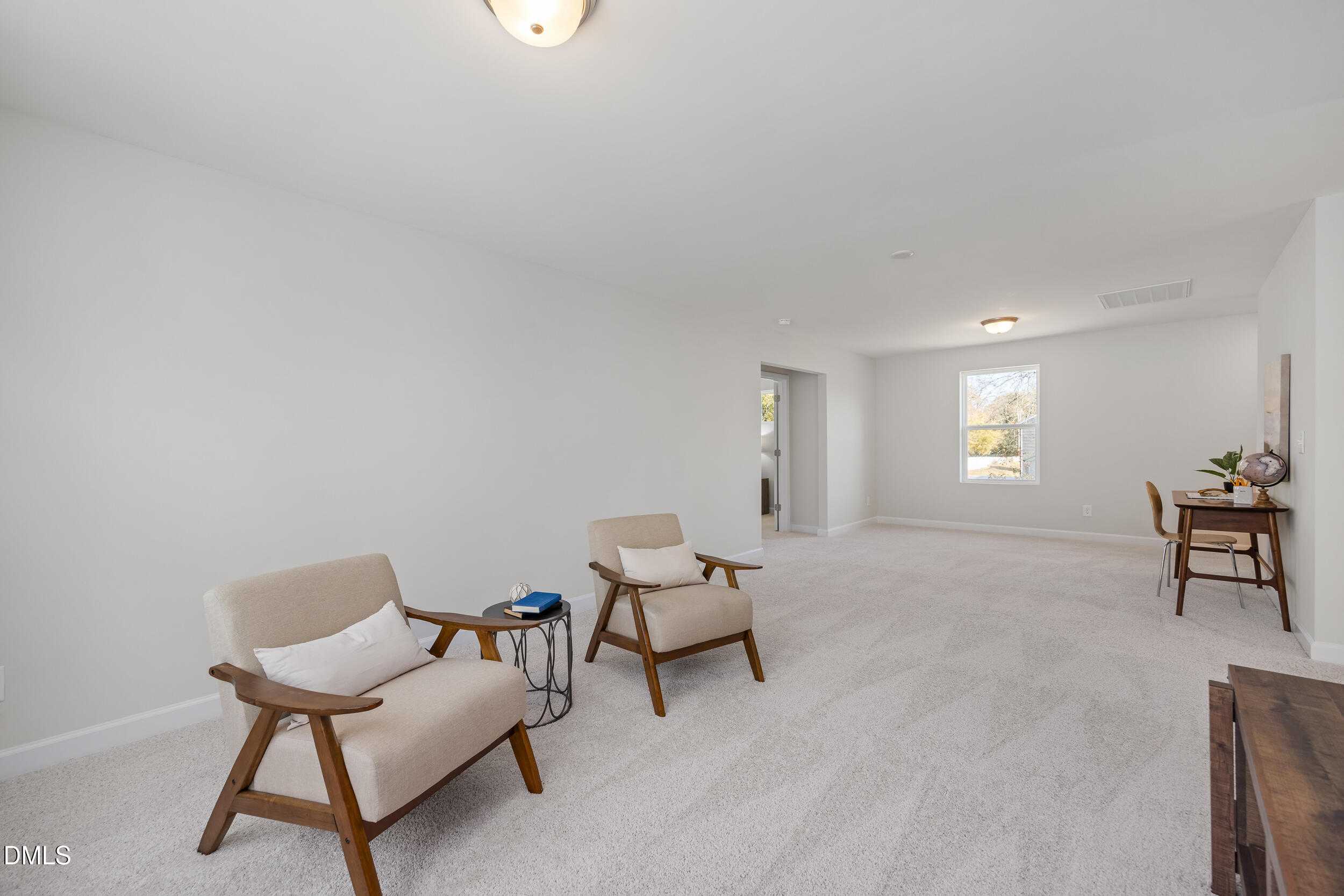 Inviting upstairs loft with beige armchairs, wooden desk, and window in Davidson Homes The Preston C, Lillington, NC