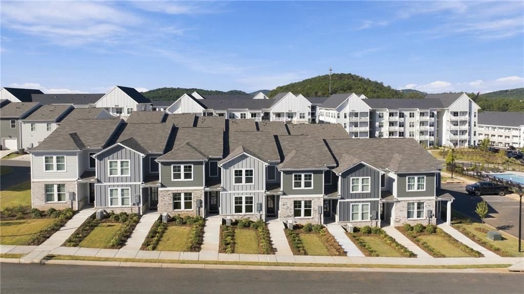 Row of new construction townhomes with gray siding and stone accents in Stegall Village, Emerson, Georgia by Davidson Homes