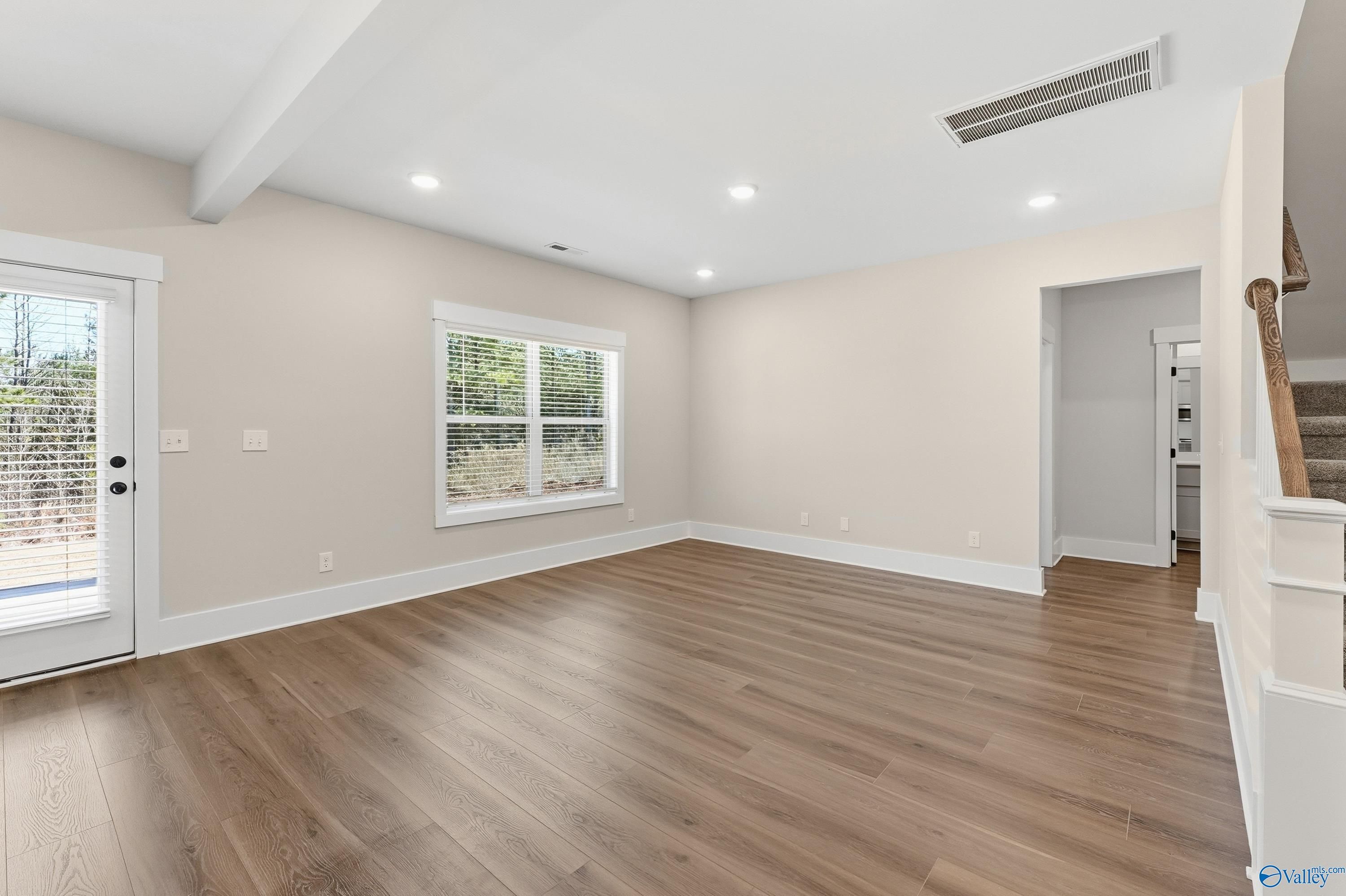 Spacious empty living room with hardwood floors, large windows, and staircase in 4-bedroom Davidson Homes Shelby A, Athens AL