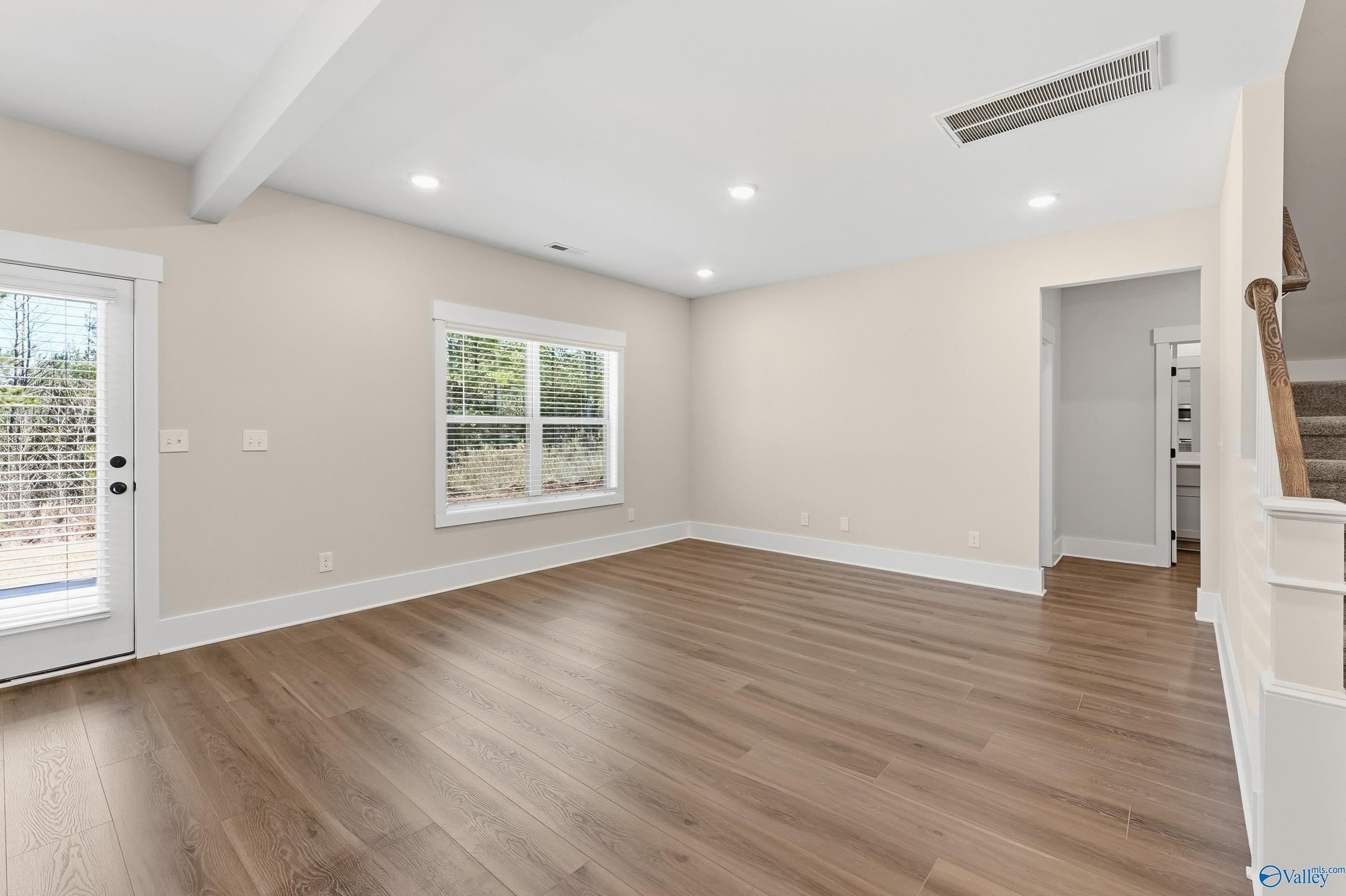 Spacious empty living room with hardwood floors, large windows, and staircase in 4-bedroom Davidson Homes Shelby A, Athens AL