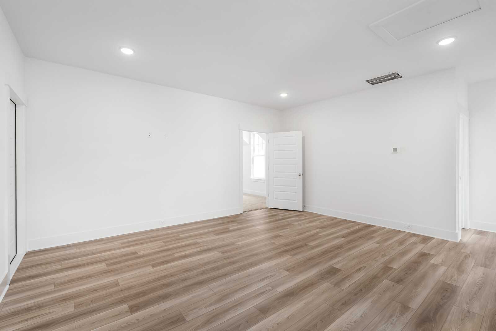 Spacious empty bedroom with light wood flooring, white walls, and recessed lighting in Davidson Homes The Hathaway, Murfreesboro, TN