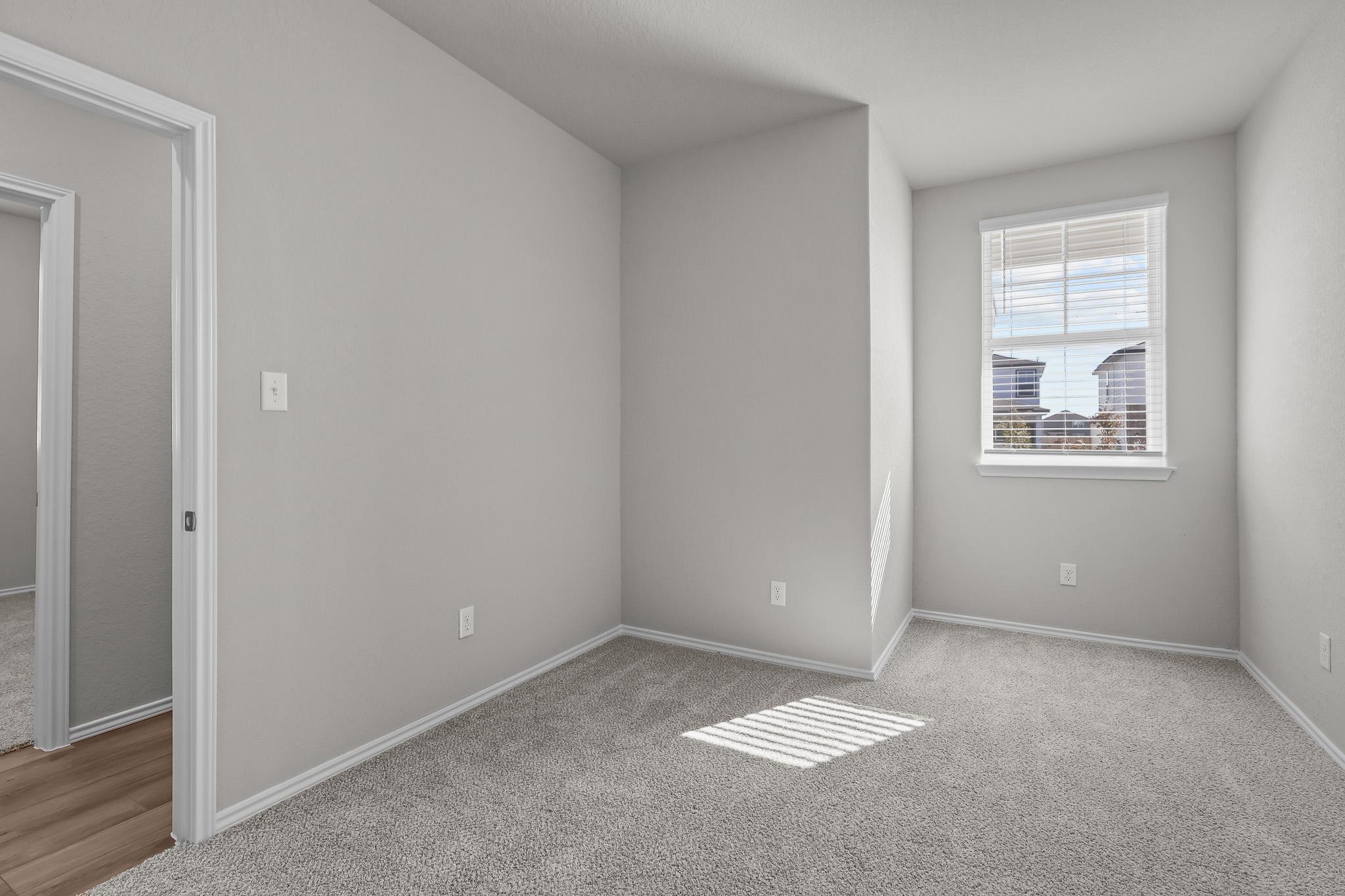 Bright secondary bedroom with plush carpeting in The Colorado floor plan by Davidson Homes in San Antonio, Texas.