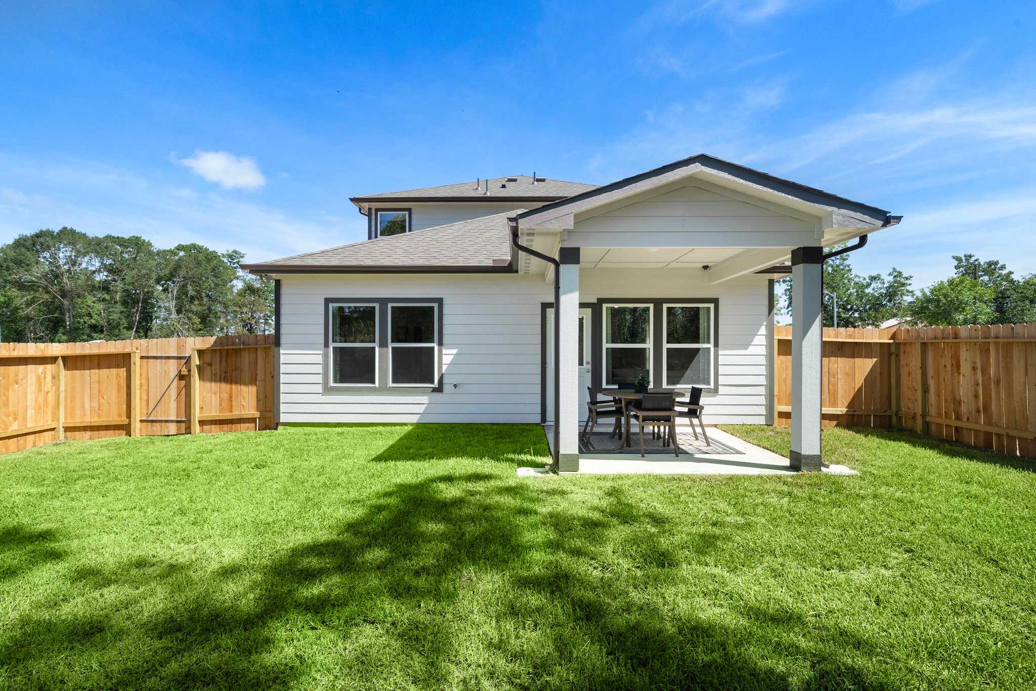 Covered back patio with seating and lush green lawn at Caney Creek Place in Conroe Texas