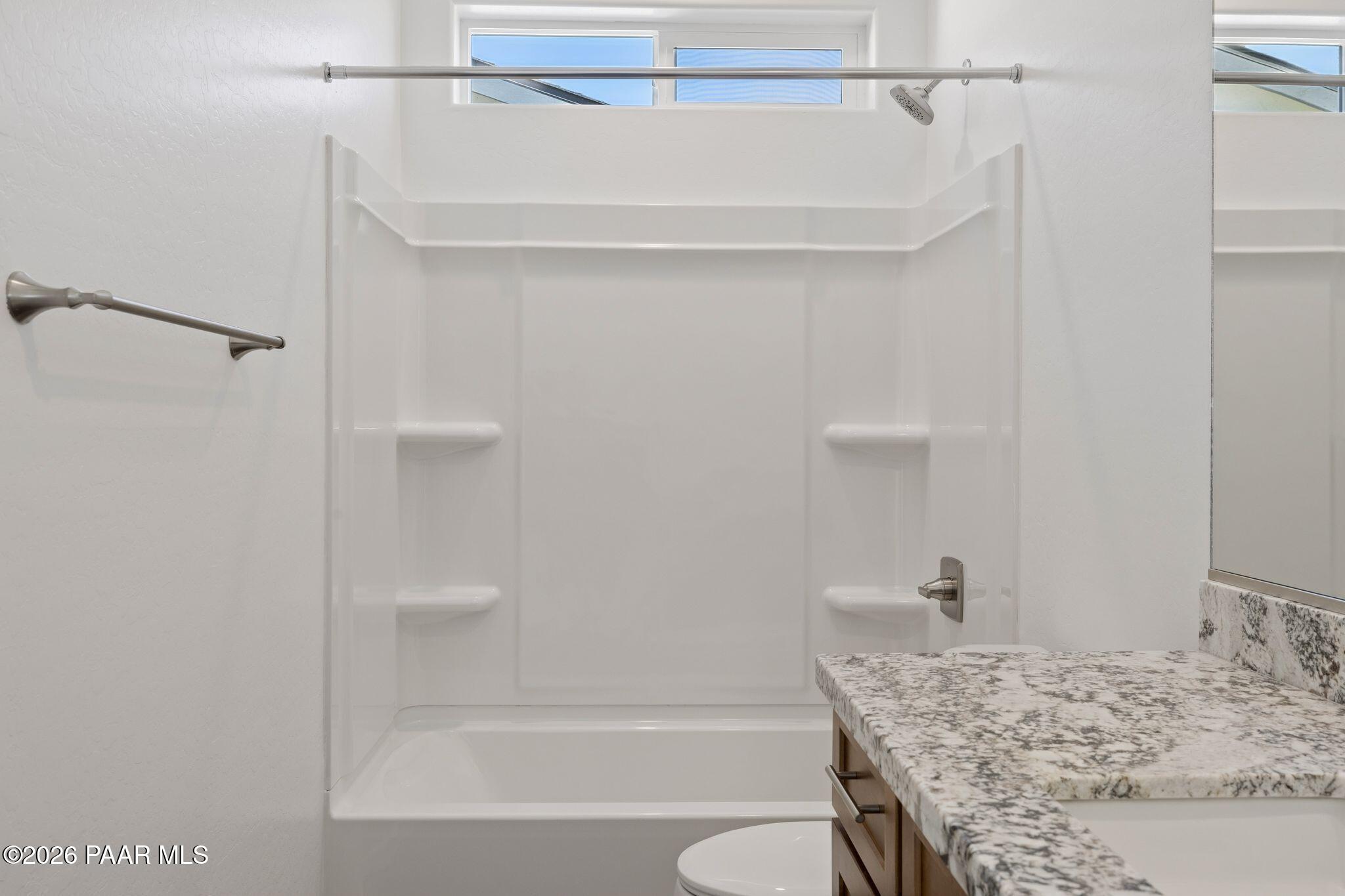 Modern master bathroom with white tub, glass shower enclosure, quartz vanity in Davidson Homes The Monarch A, Prescott AZ