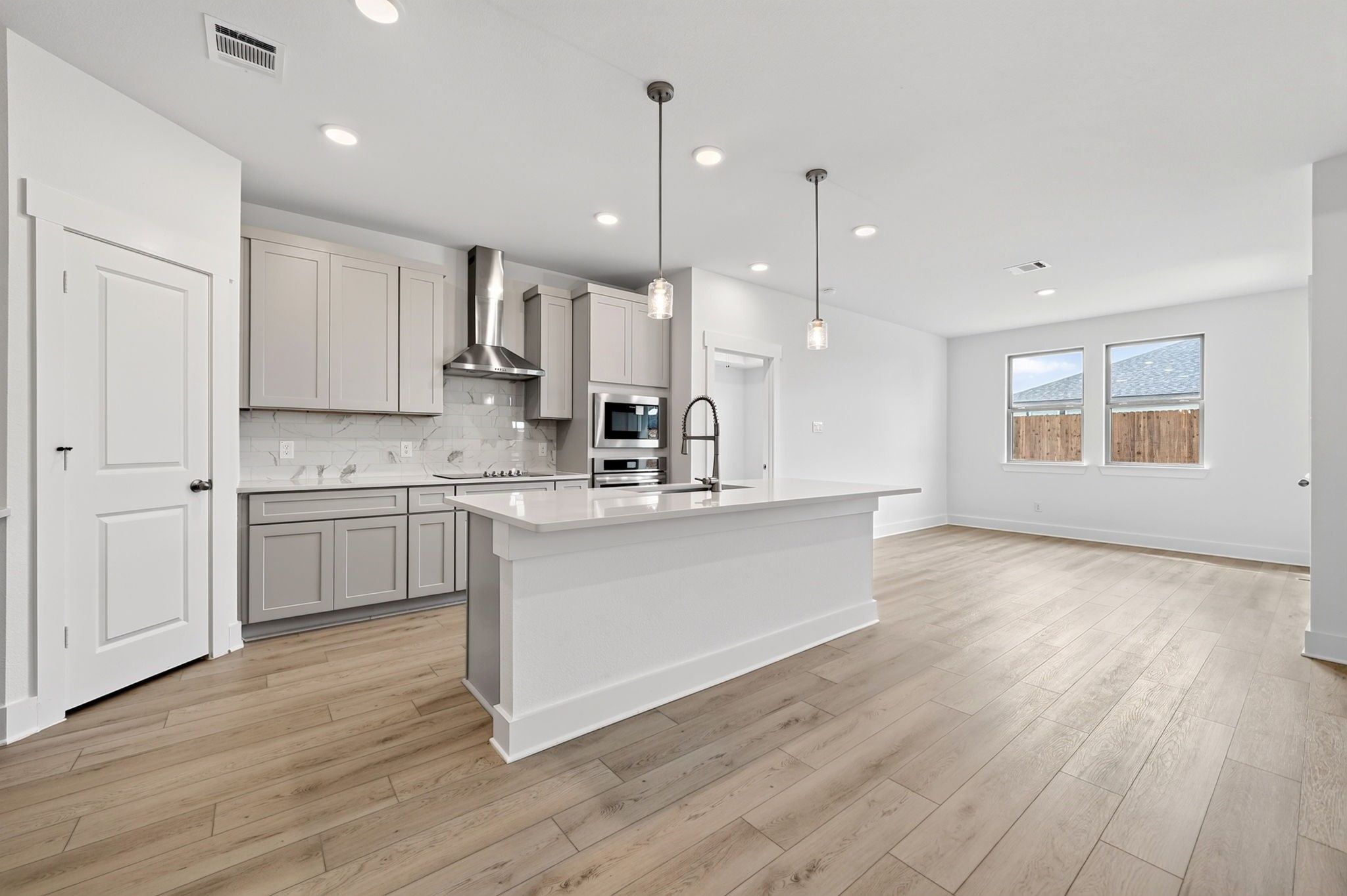 Open-concept kitchen with white island, pendant lights, and wood-look flooring in Davidson Homes Holly F plan, Josephine, TX
