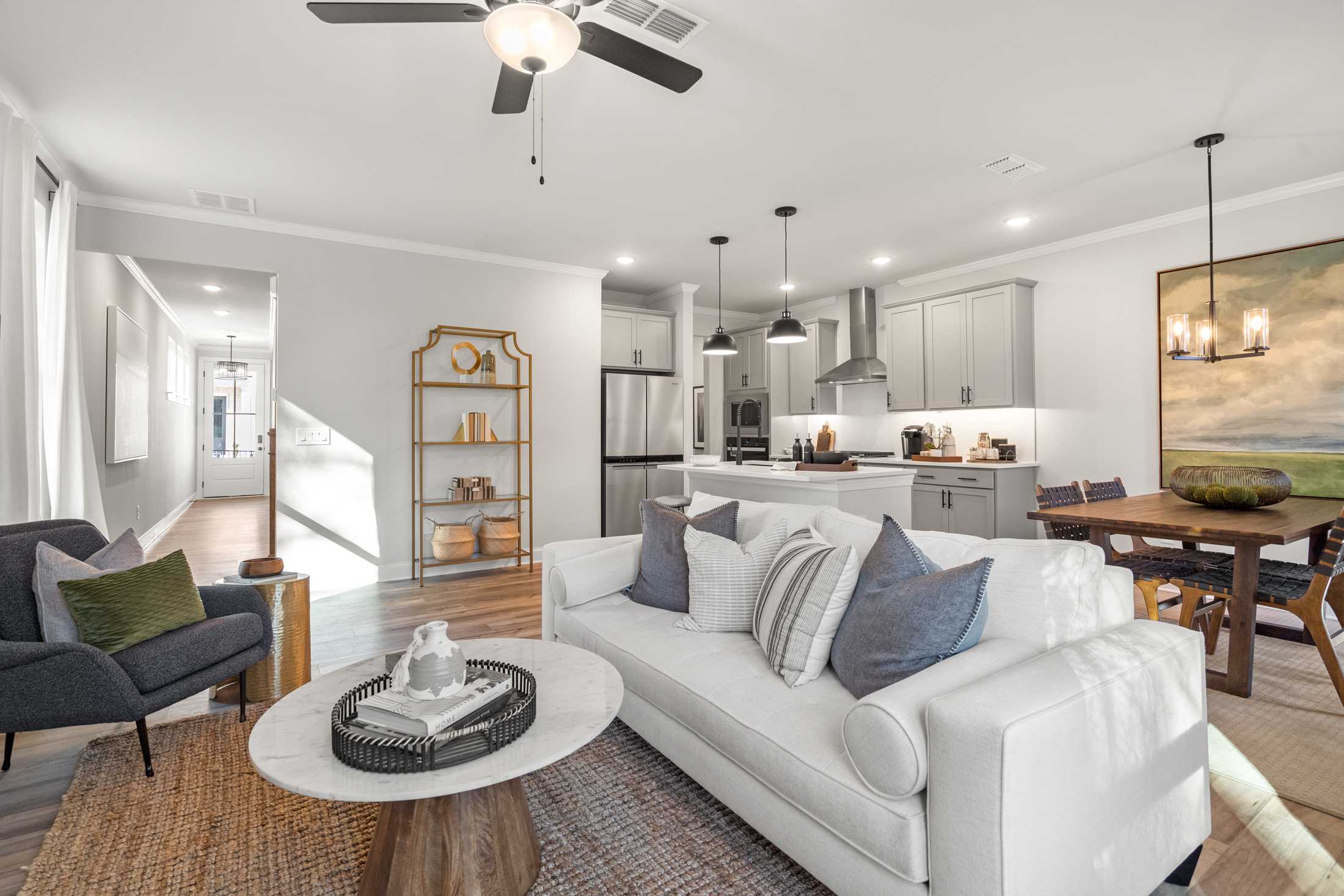 Spacious open-concept living room at Rosehill Townhomes in Marietta GA with white sofa, round coffee table, dining area, and modern kitchen