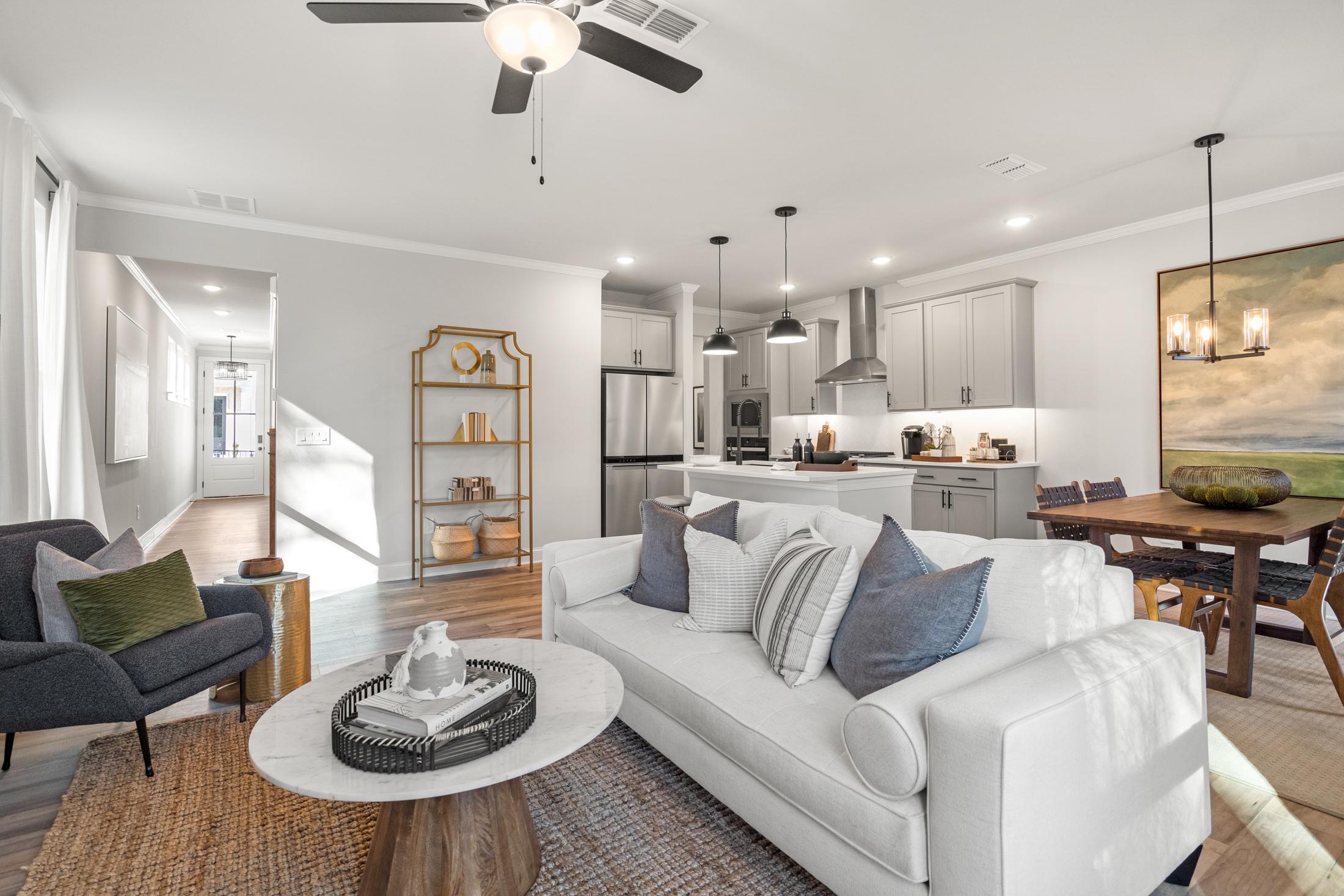 Spacious open-concept living room at Rosehill Townhomes in Marietta GA with white sofa, round coffee table, dining area, and modern kitchen