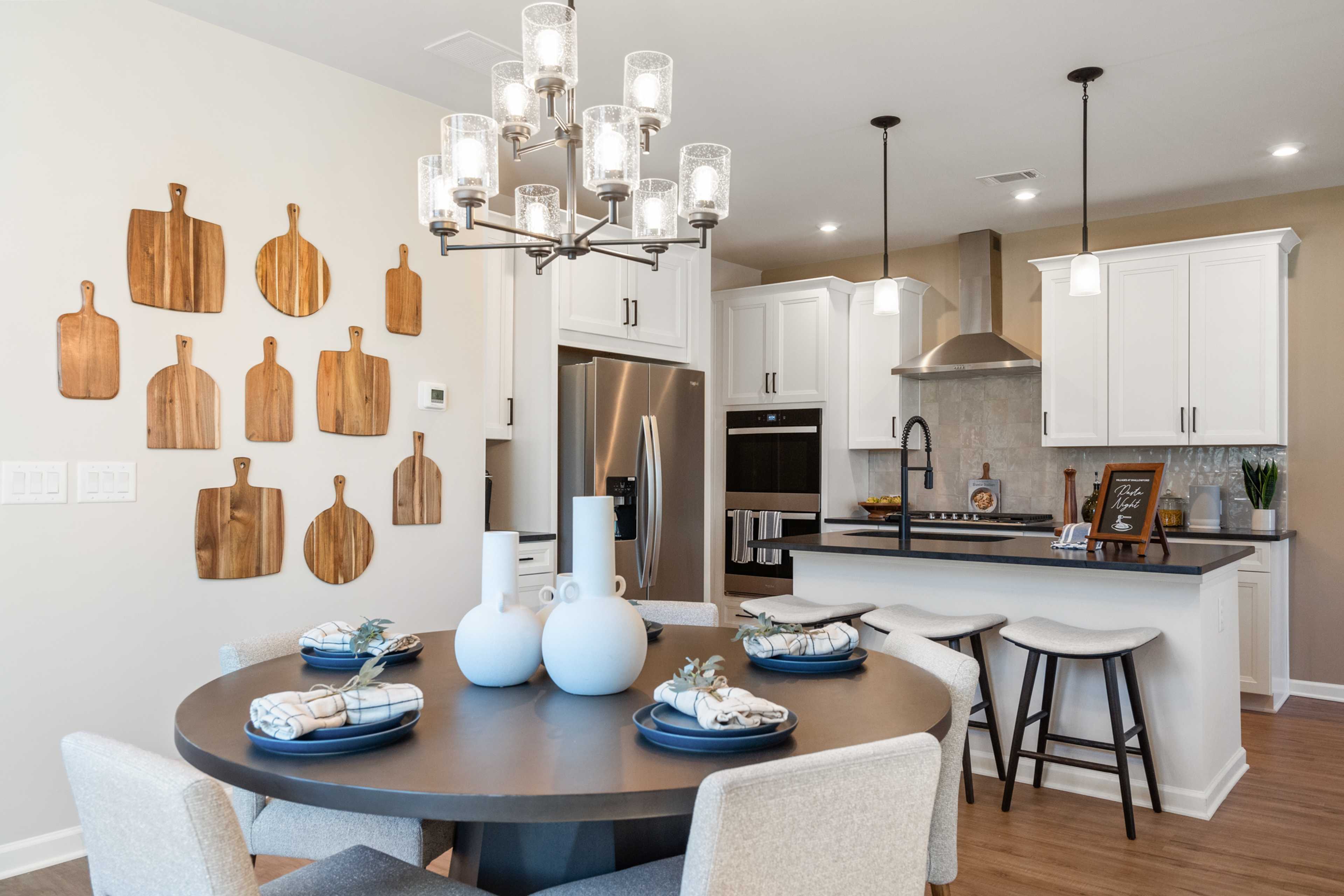 Spacious open-concept kitchen at The Village at Shallowford in Kennesaw GA with white cabinets, island, chandelier and round dining table