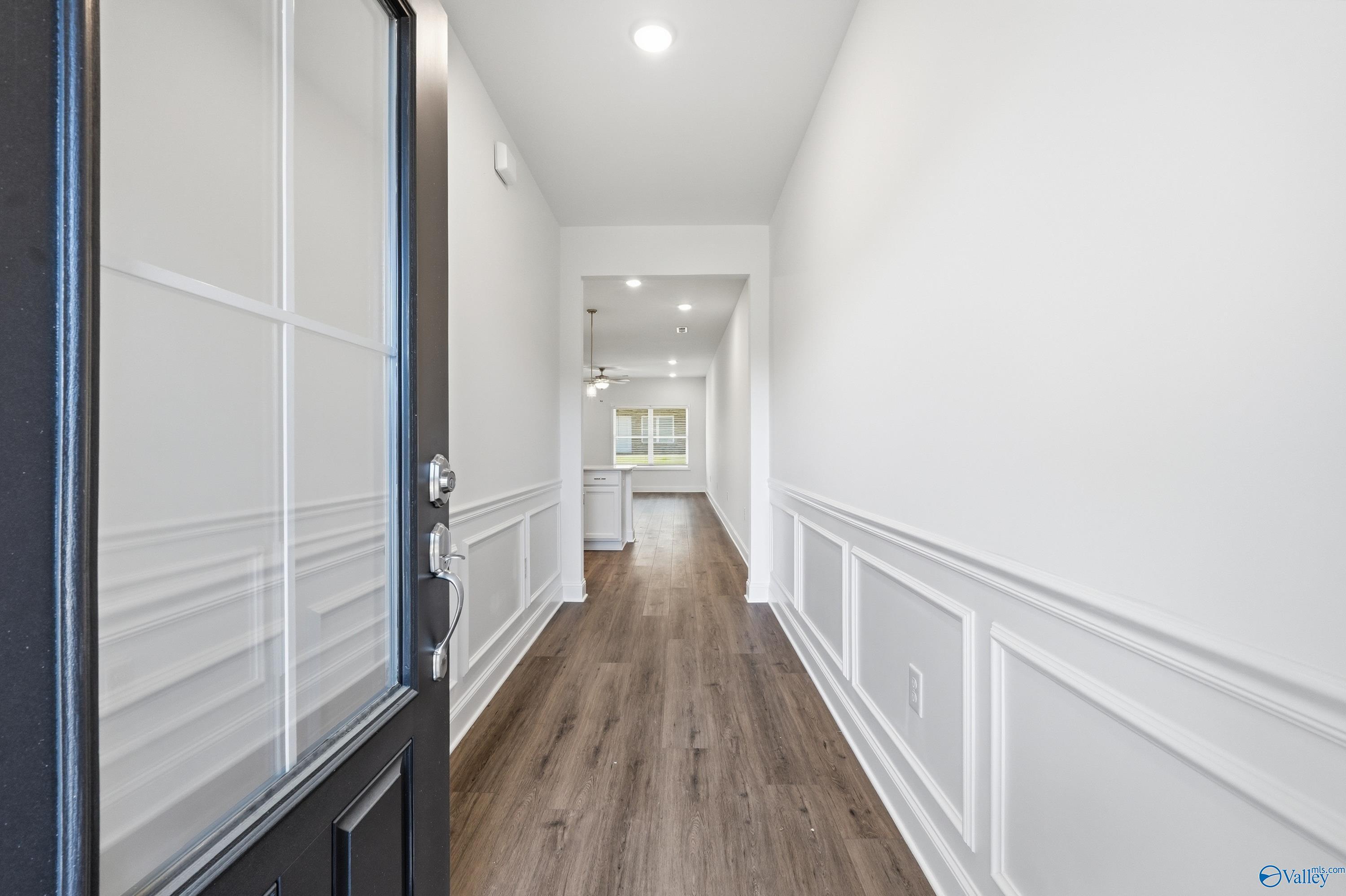 Elegant hallway with wainscoting, hardwood floors, and recessed lighting leading to kitchen in Davidson Homes The Cumberland D, Decatur, Alabama