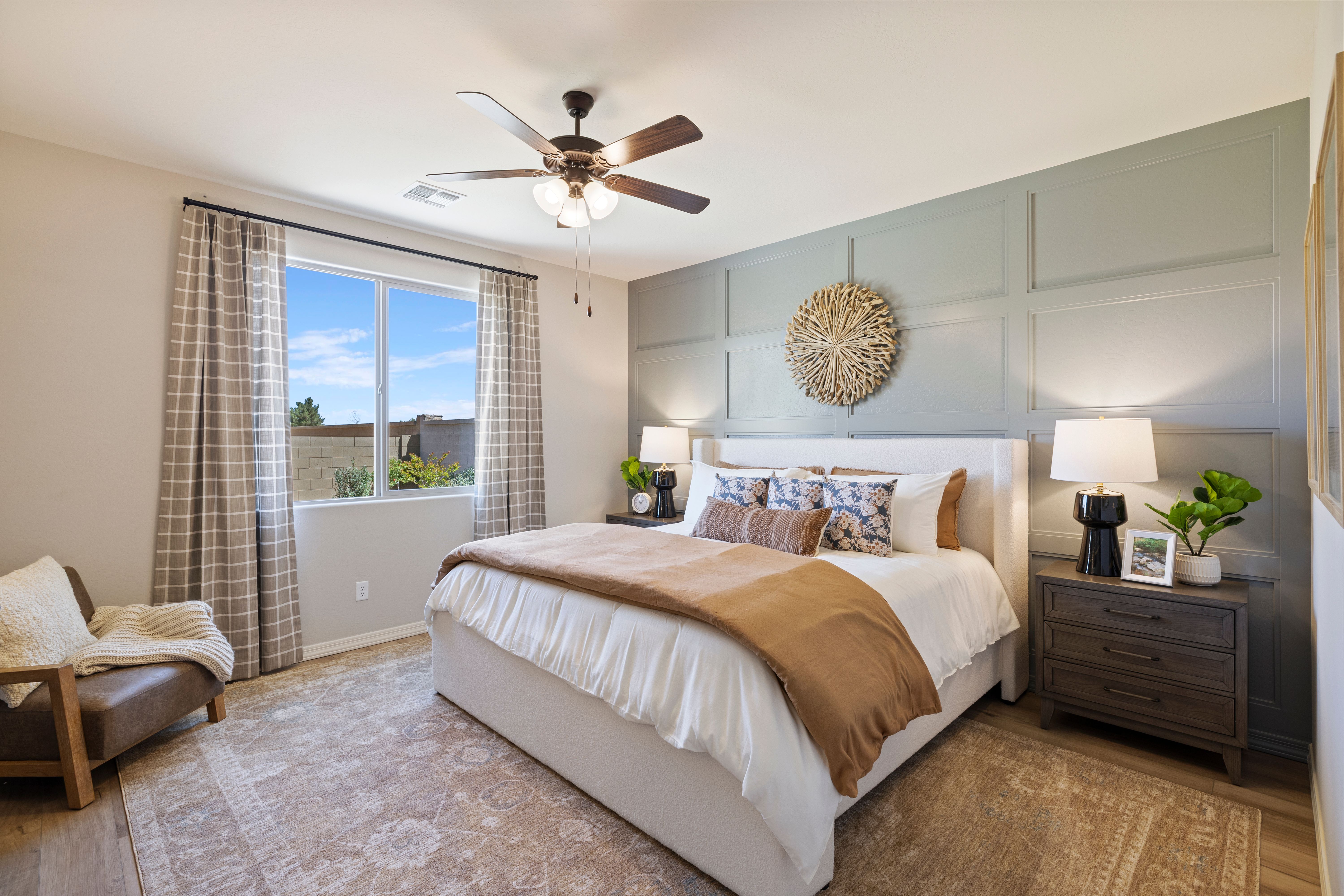 Modern primary bedroom at North Ridge Pronghorn Ranch in Prescott Valley AZ with white upholstered bed, greige accent wall, and window view