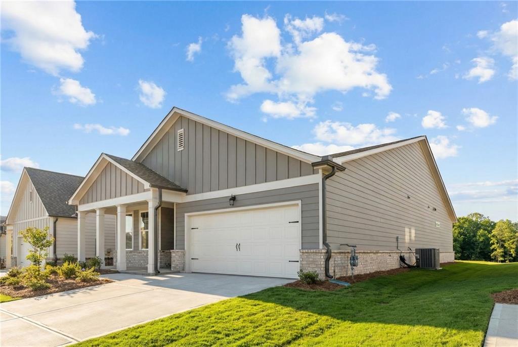 Modern 1-story gray home with 2-car garage, brick accents, and landscaped yard in Kelly Preserve, Loganville, Georgia - Davidson Homes Edison B