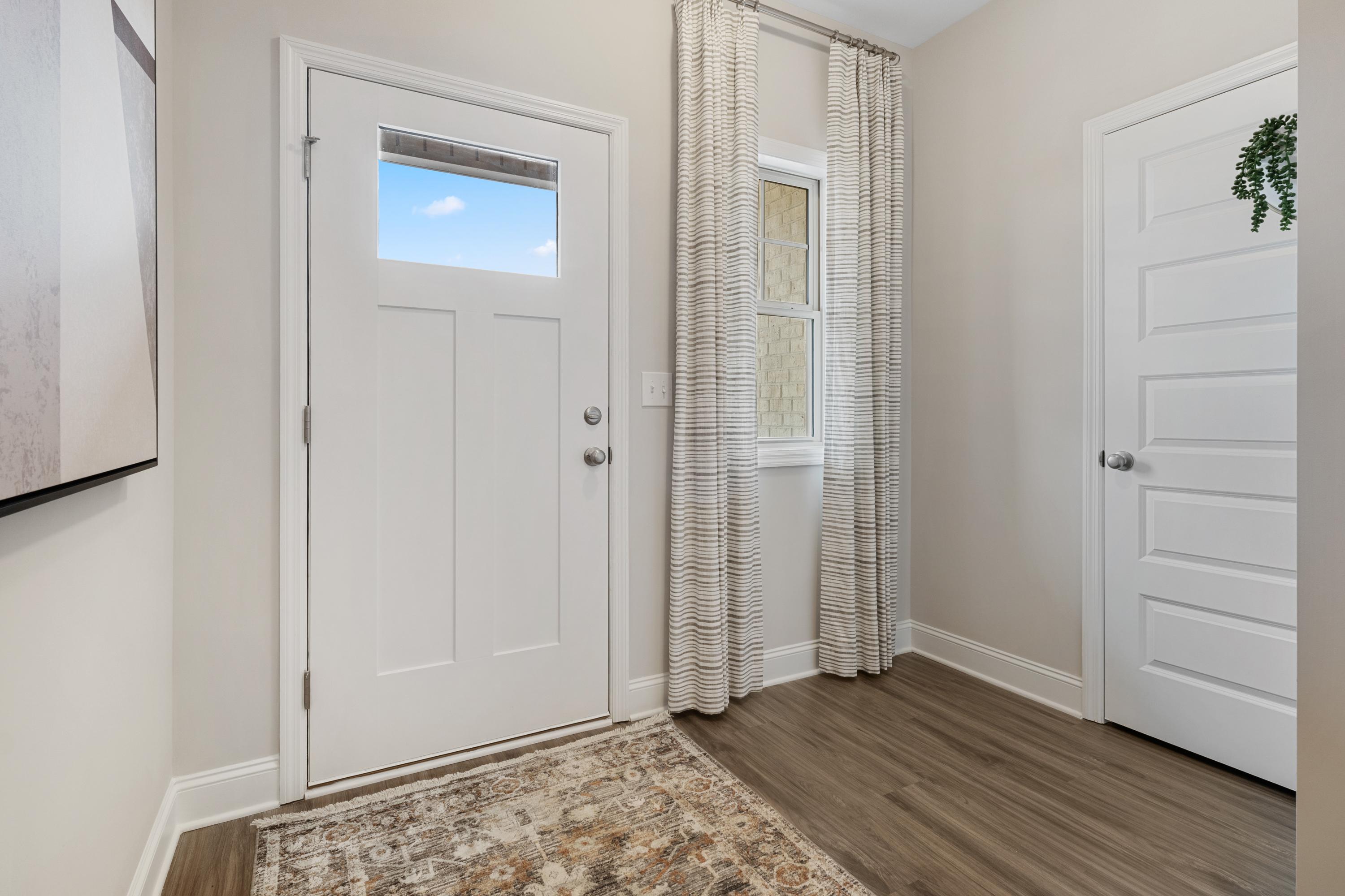 Spacious entryway at The Retreat at Cain Park in Hartselle Alabama with white doors, striped curtains, hardwood floors