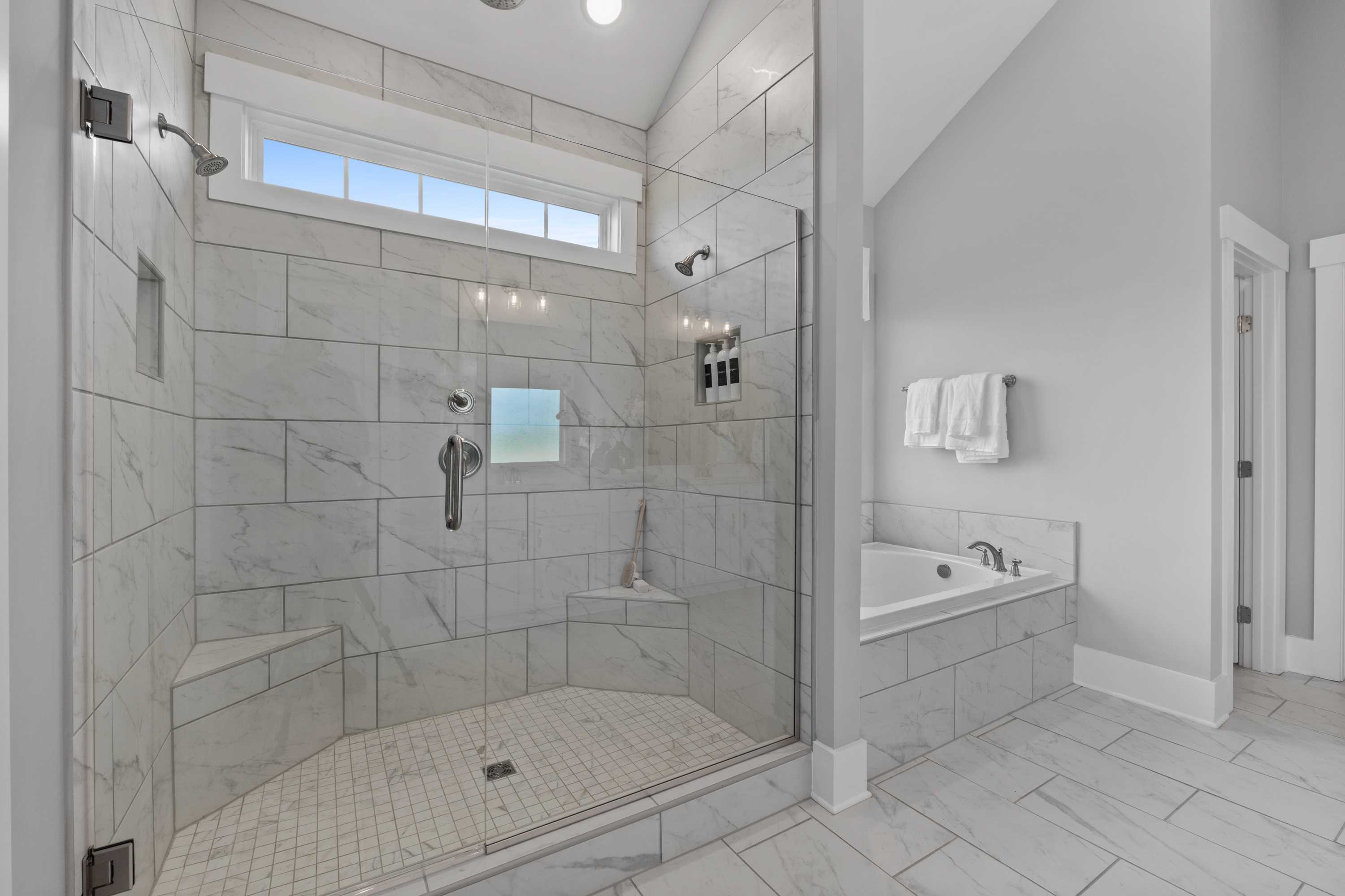 Luxurious master bathroom at Creekside in Harvest Alabama with walk-in glass shower, freestanding tub, subway tile walls