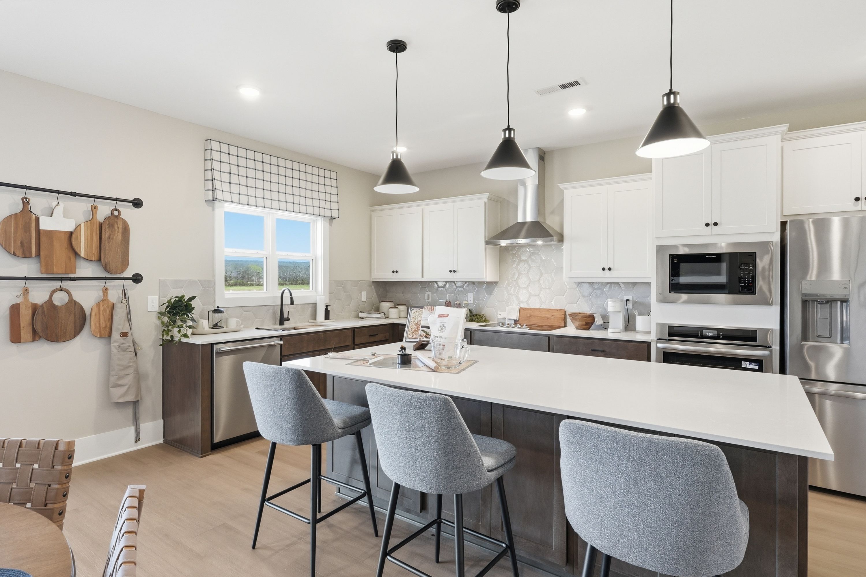 Modern kitchen in Berry Cove home, New Market Alabama with white shaker cabinets, large island, stainless steel appliances, and pendant lights