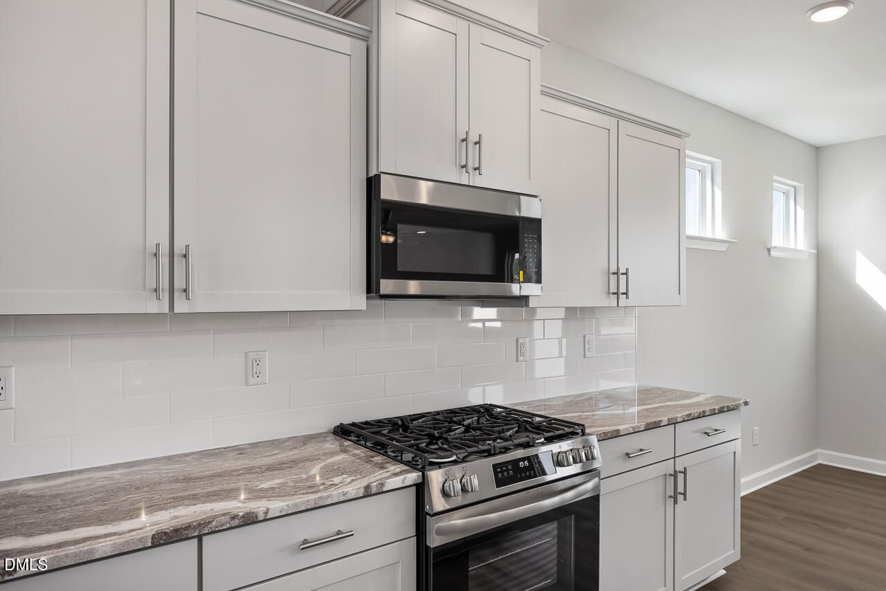 Modern white shaker kitchen with subway tile backsplash, quartz countertops, stainless gas range in The Willow G by Davidson Homes, Angier, NC