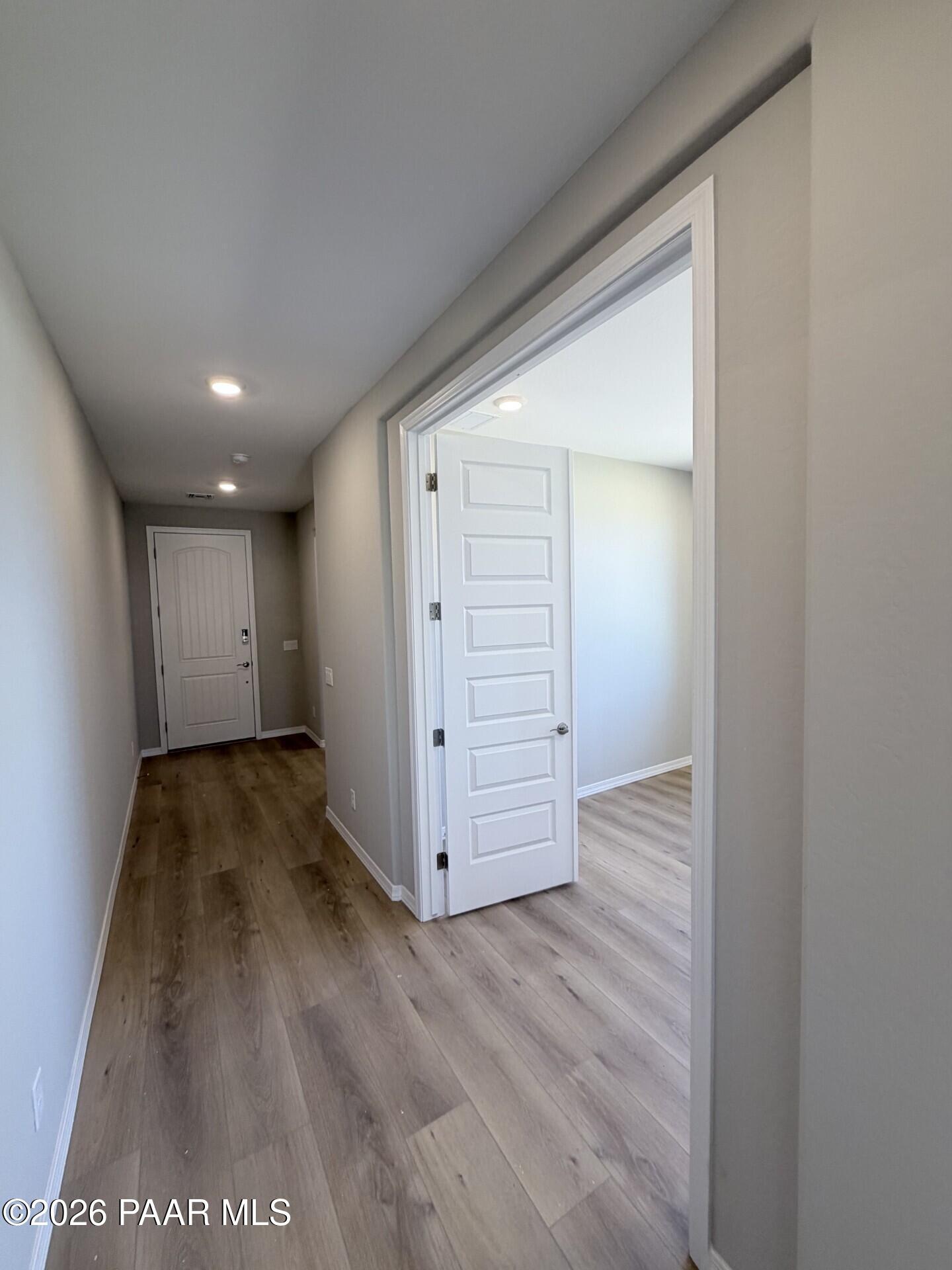 Bright hallway with light wood-style flooring leading to a bedroom in The Frontier A floor plan at North Ridge, Prescott.