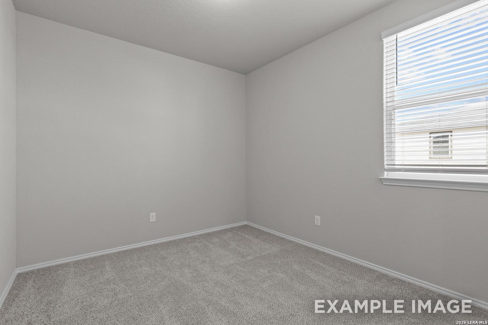 Bright empty bedroom with light gray walls, carpet flooring, and large window in Davidson Homes The Colorado D, San Antonio