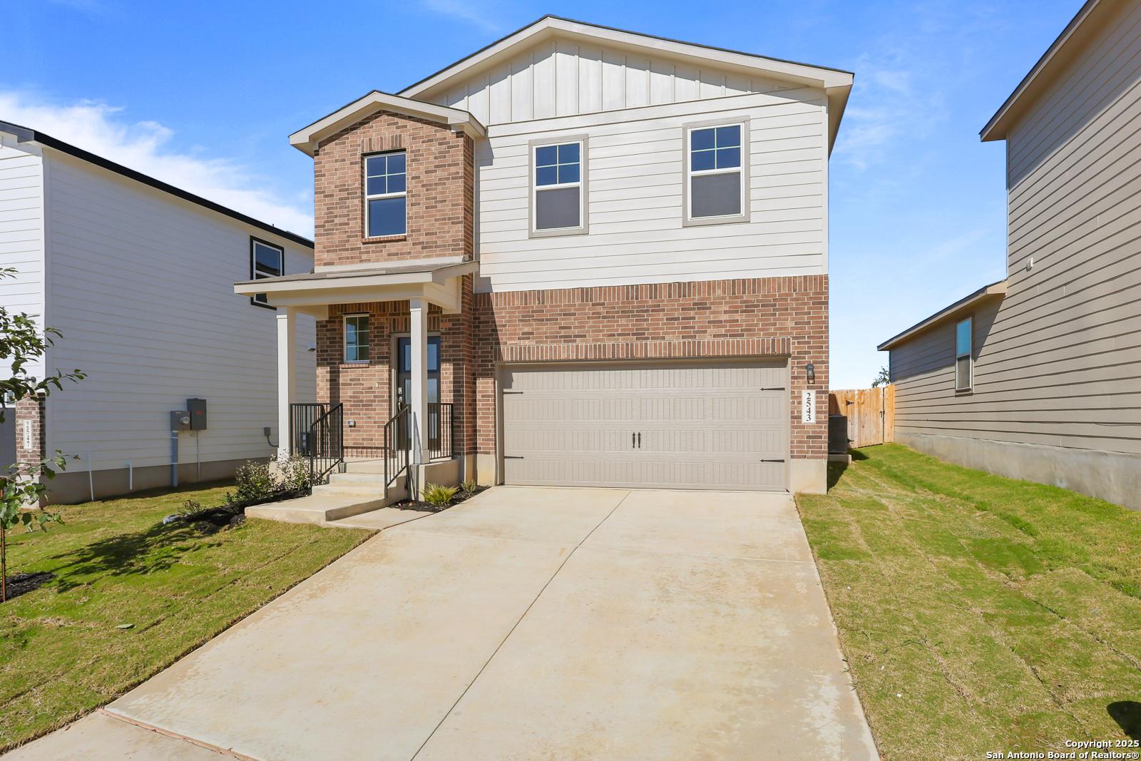 Two-story brick and siding home with 2-car garage, front porch, and driveway in Applewhite Meadows, San Antonio, Texas